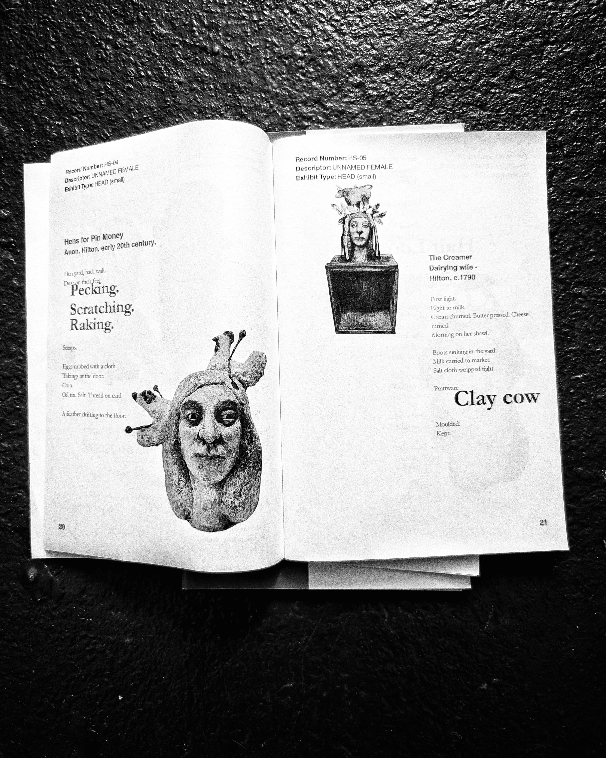 Open book featuring black and white illustrations and text about a head sculpture called 'Clay Cow', set against a textured dark background.
