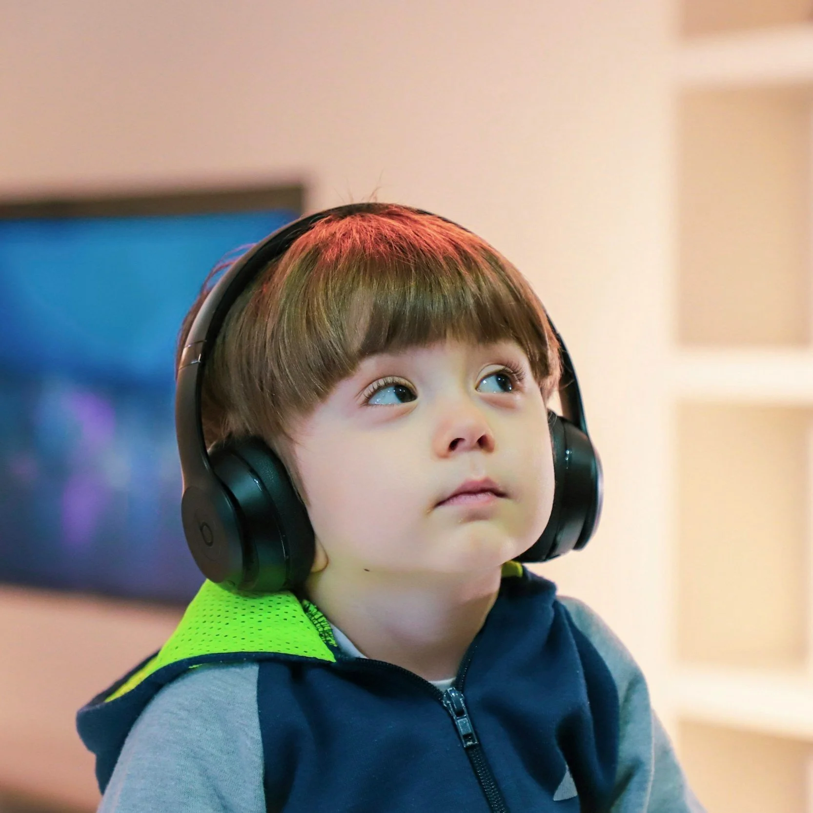 Young boy with brown hair wearing headphones and a navy and gray jacket, looking curious, representing neurodivergent-friendly therapy and support at Black Onyx Counselling in London, Ontario