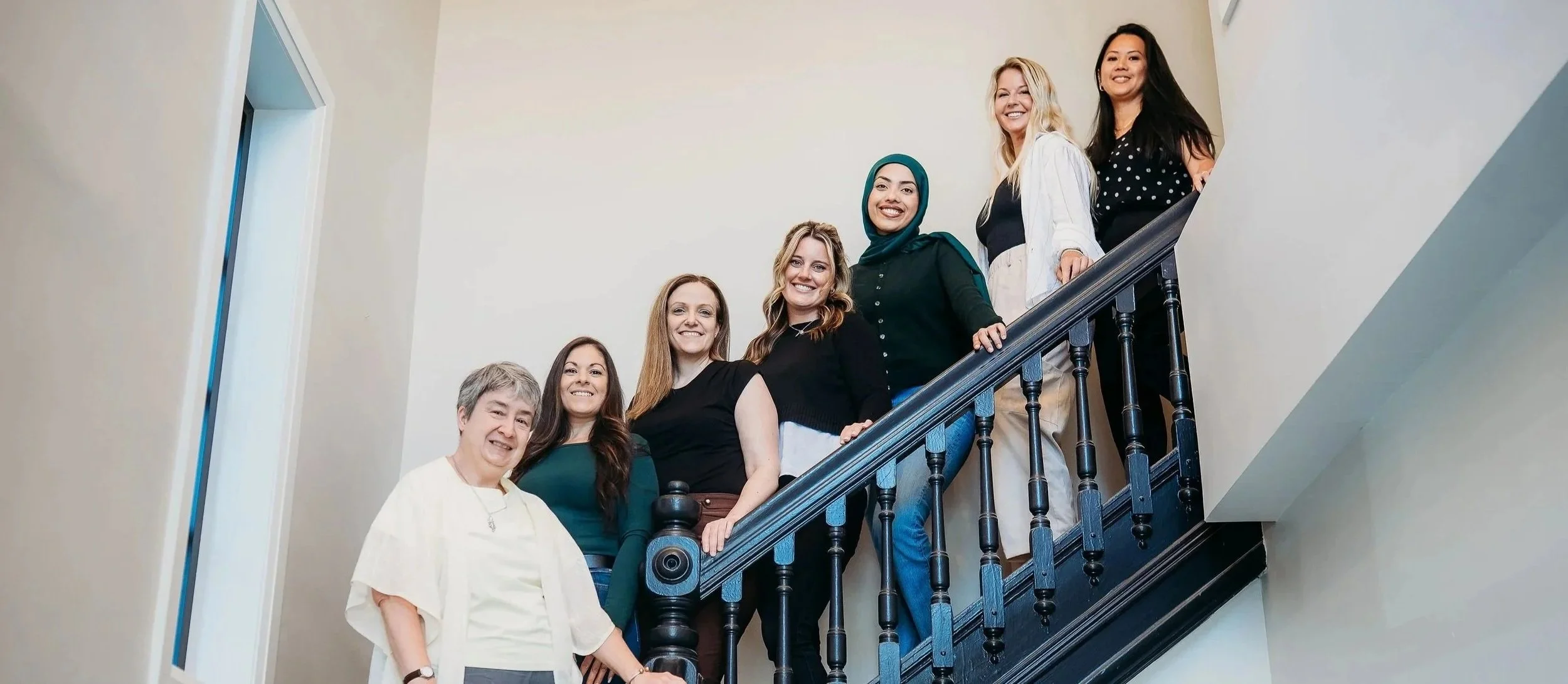 The Black Onyx Counselling team of therapists standing together on a staircase in London, Ontario