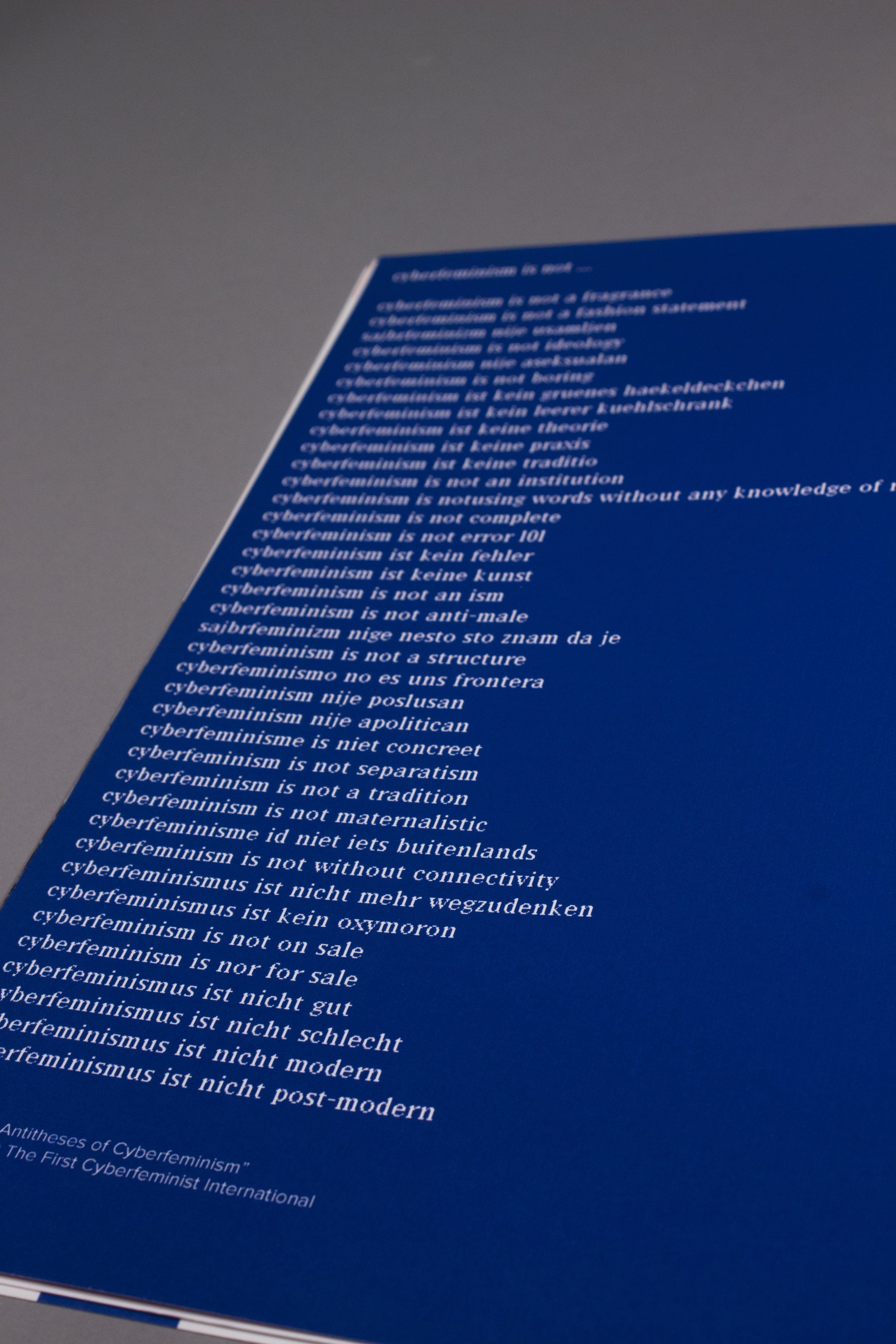 An image of the "100 Antitheses of Cyberfeminism." It is white text on a blue background.