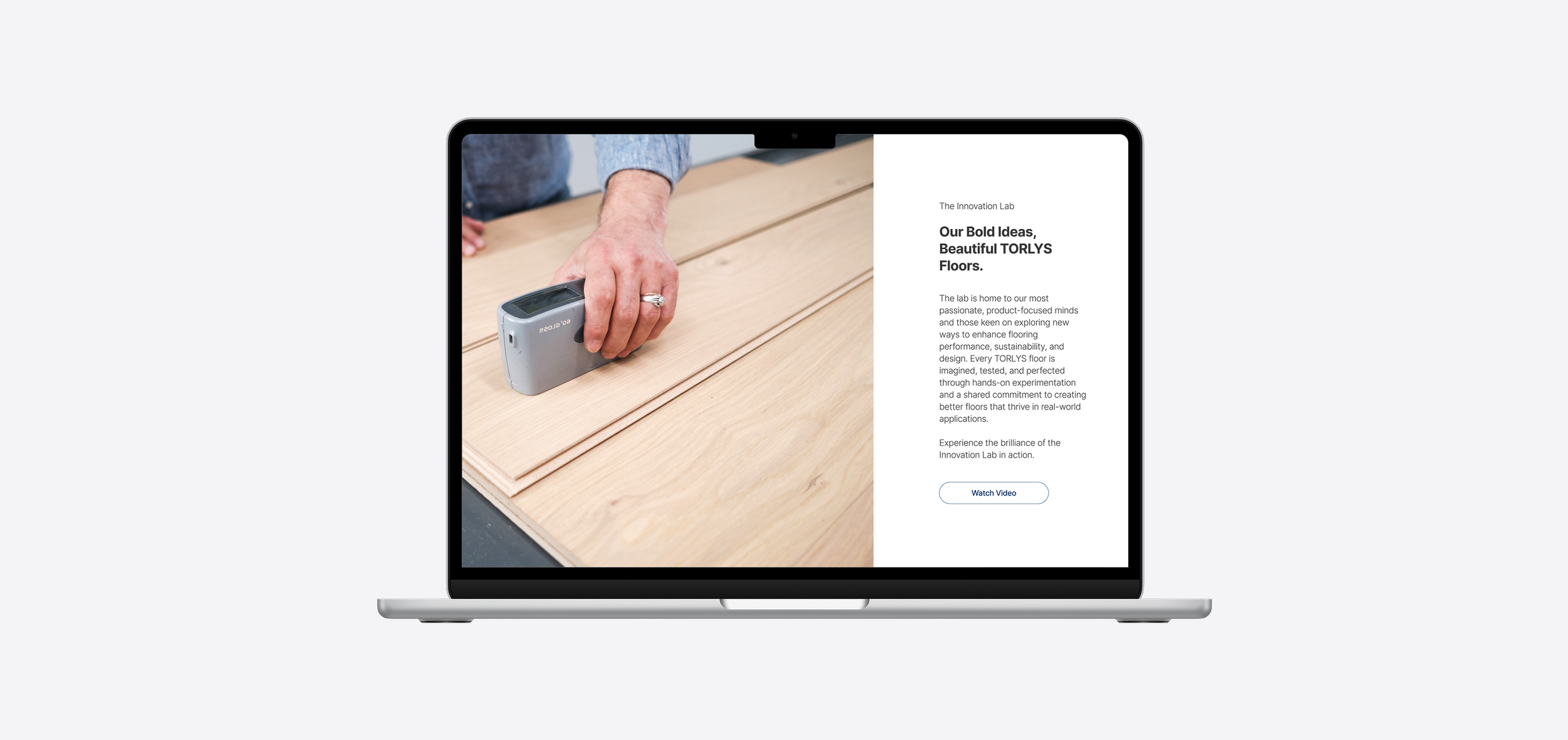 Laptop displaying a webpage about flooring innovation, with an image of a hand vacuuming a wooden floor.