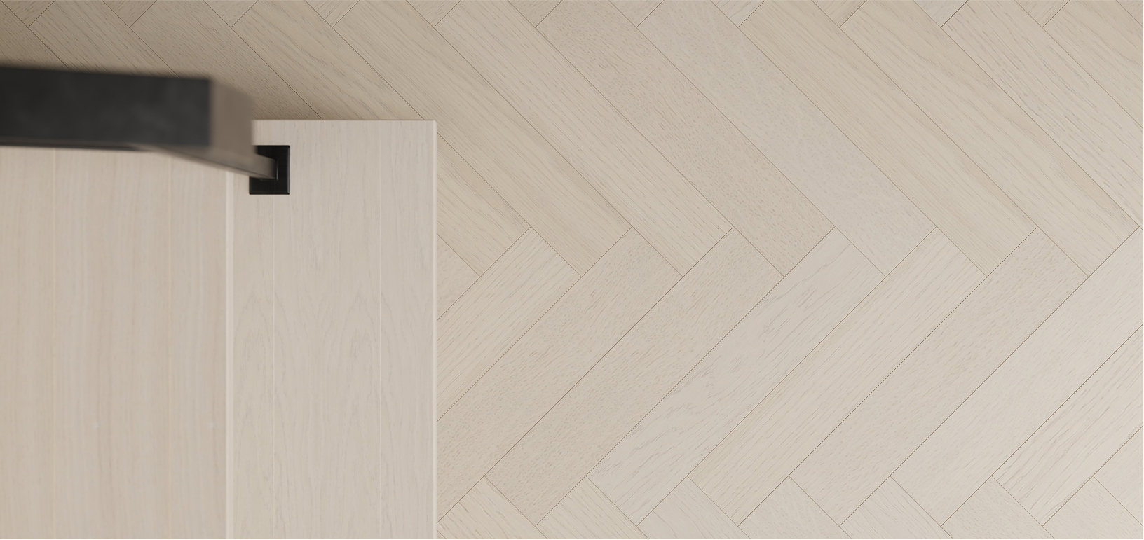 Top-down view of a light-colored wooden floor with a corner of a white piece of furniture and a black object on top.