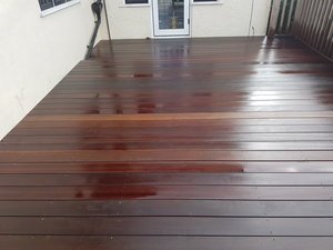 Wet wooden deck outside a house with a sliding door and railing.