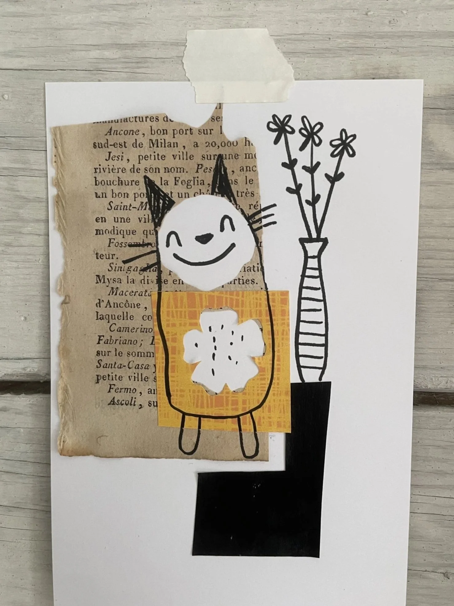 Paper collage of a smiling cat figure in an orange sweater on an old book page, beside a black and white striped vase of flowers.