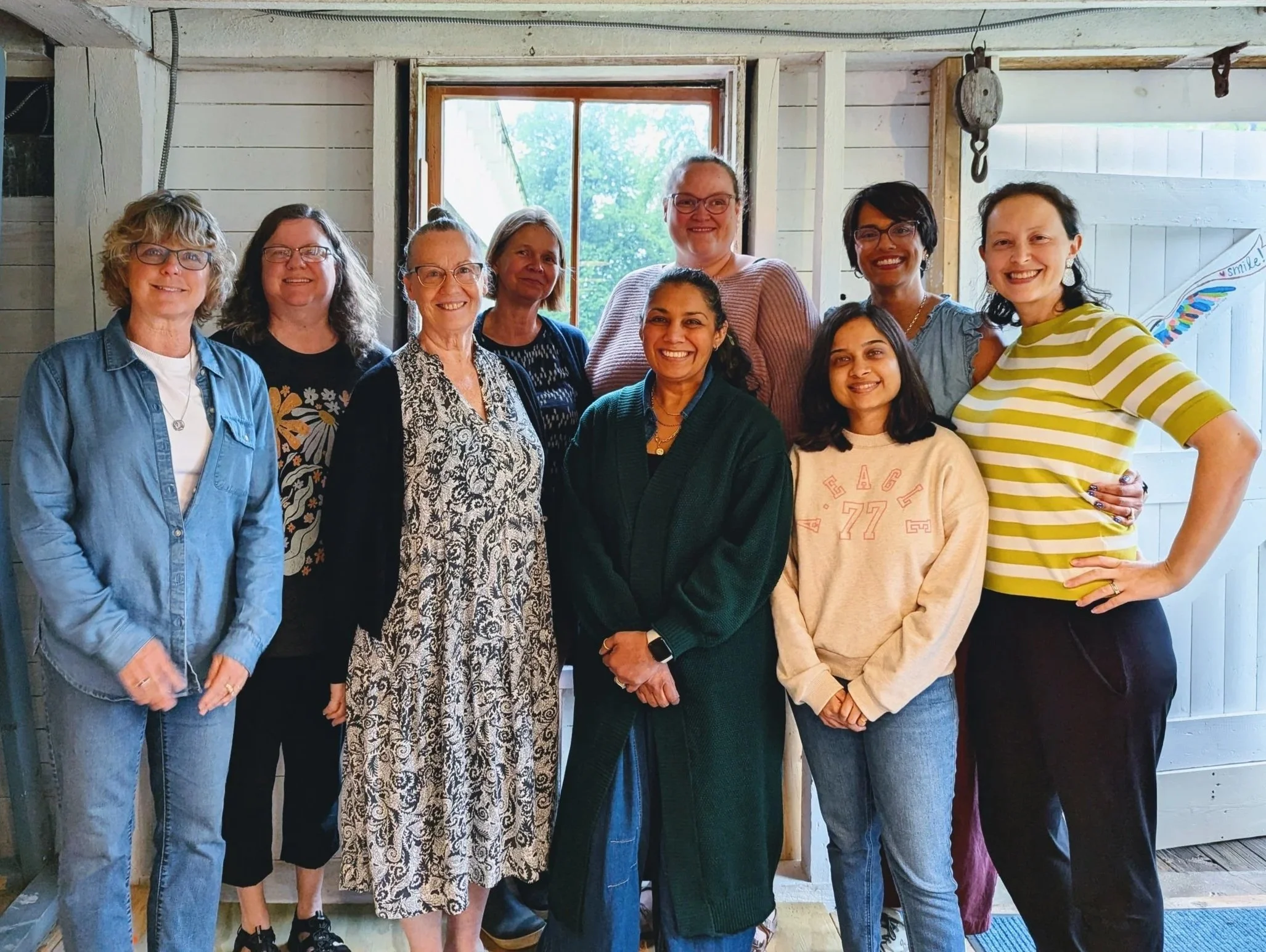 Group of retreat artists and instructor smiling together in the barn studio by the open white door