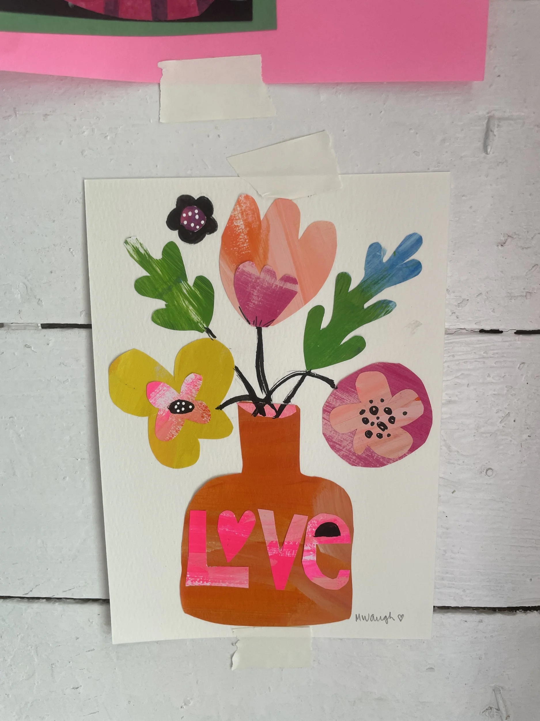 Paper collage of an orange vase labeled Love holding pink, yellow and green paper flowers, taped to the barn wall.