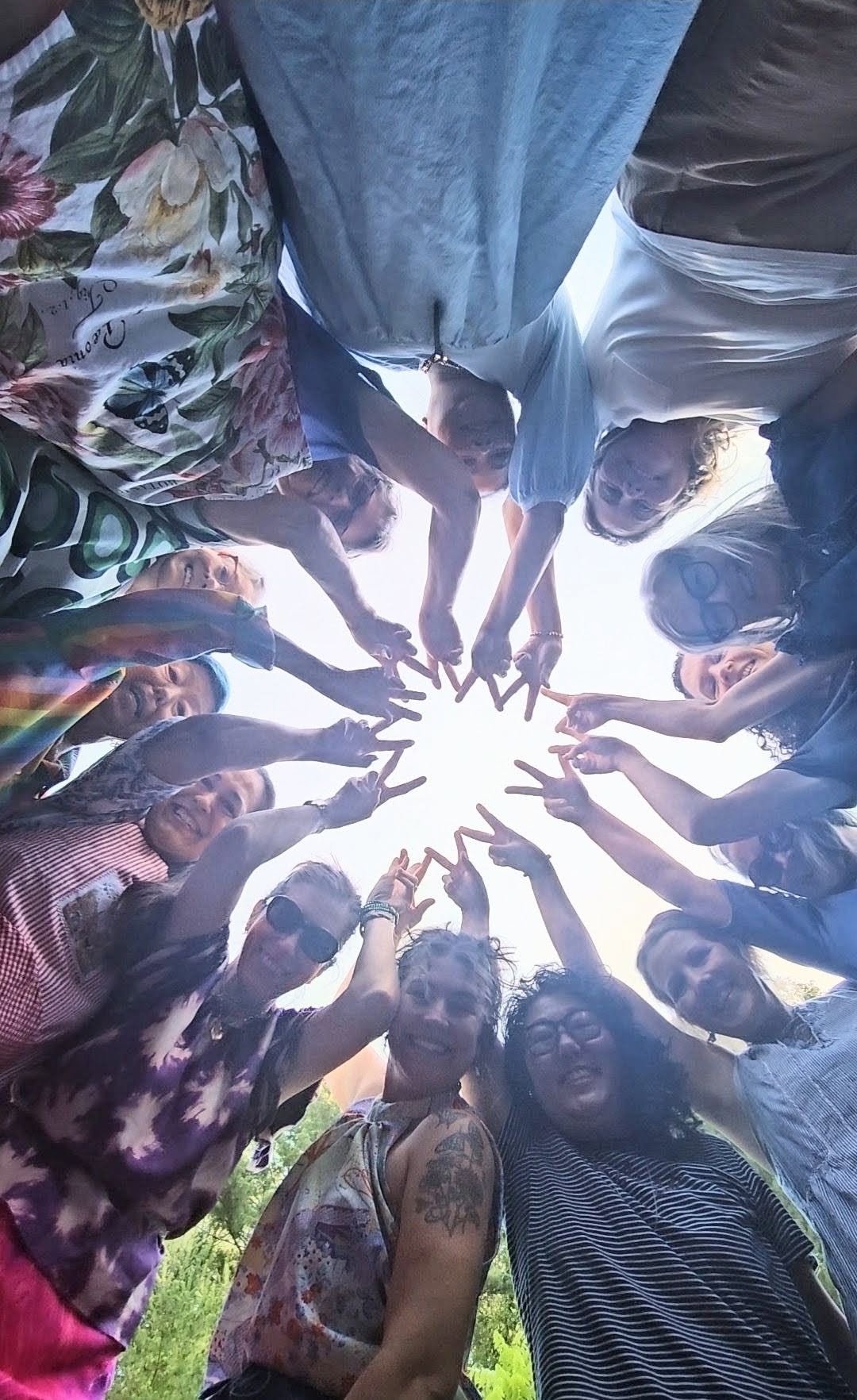 View from below of retreat artists standing in a circle with their fingertips touching in the center