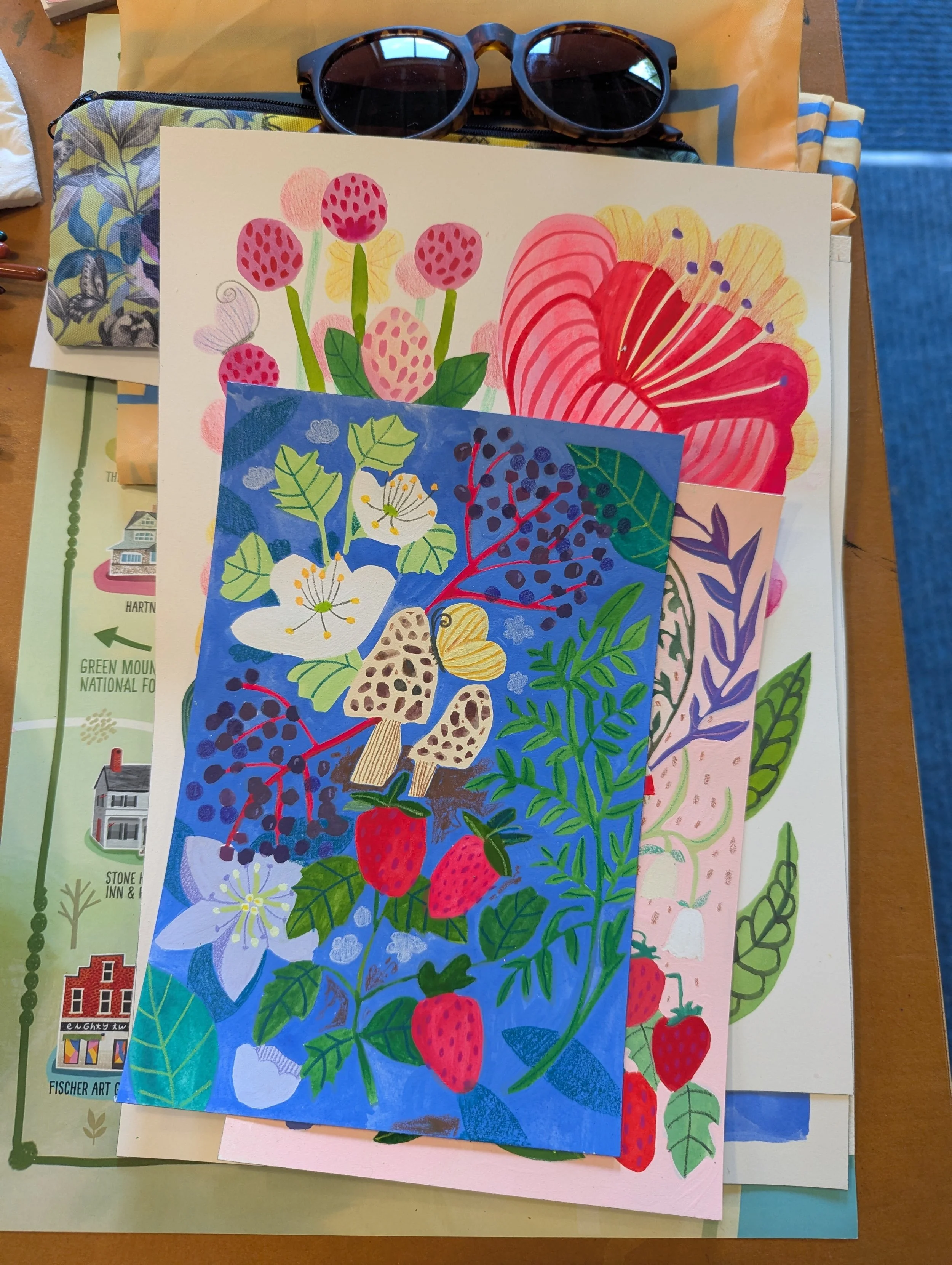 Stack of finished gouache paintings of florals, mushrooms and berries on bright blue and pink backgrounds