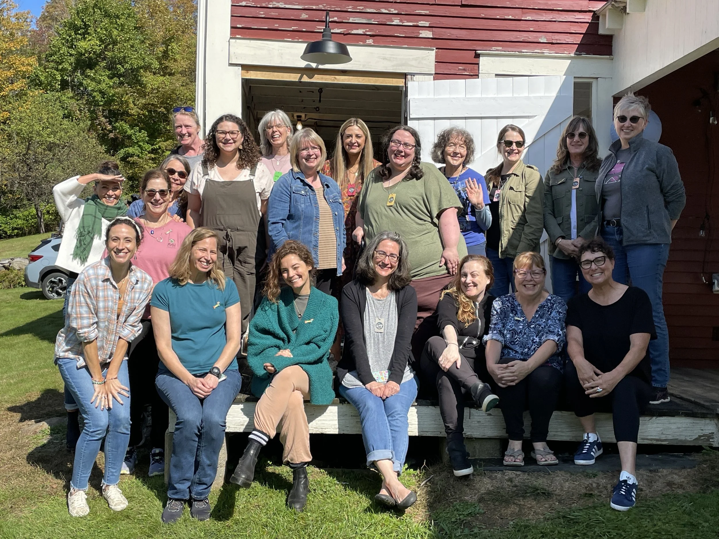 Large group of retreat artists posed on the barn porch steps in autumn sunshine