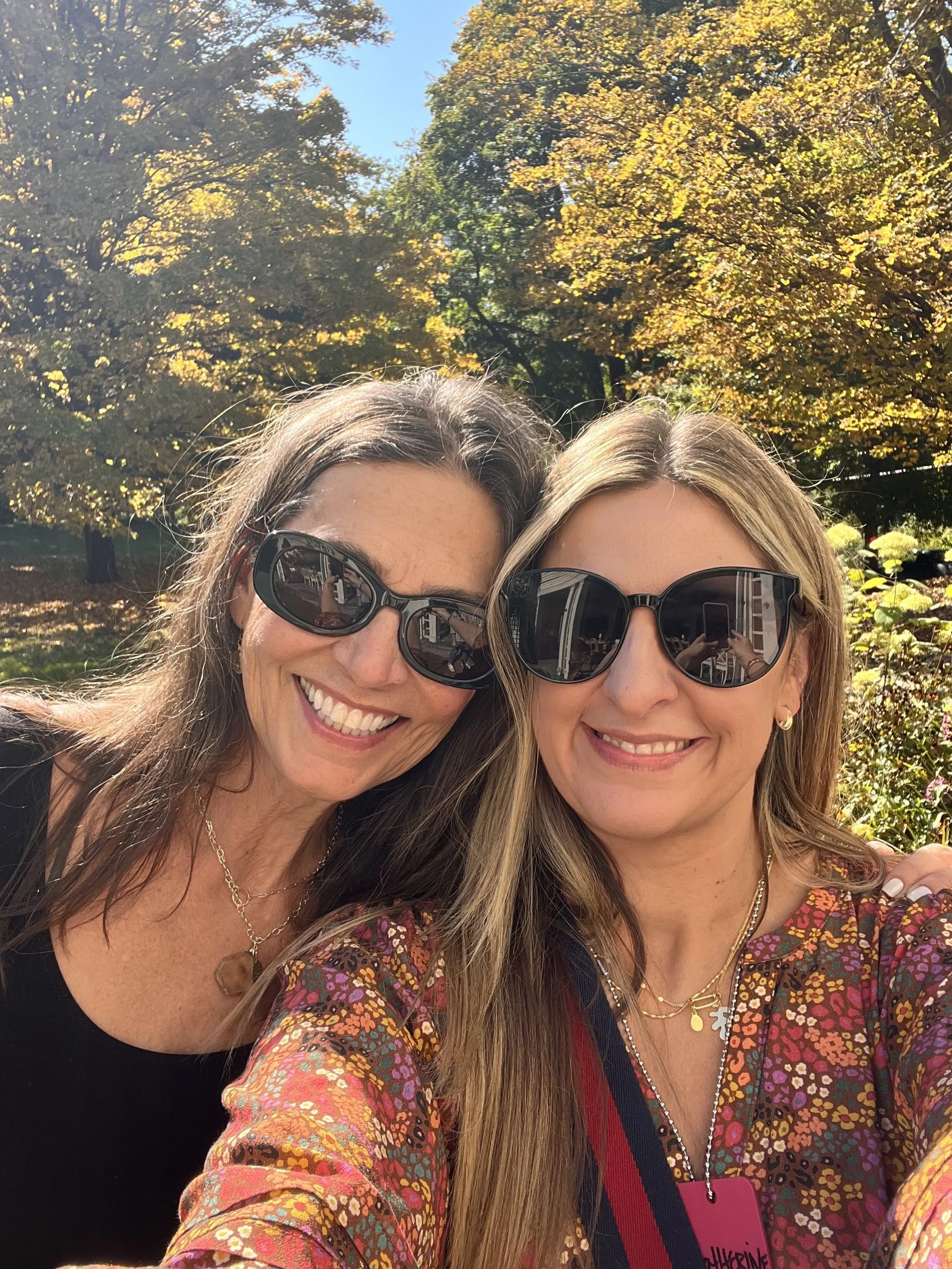 Two smiling artists taking a selfie under yellow autumn maple trees