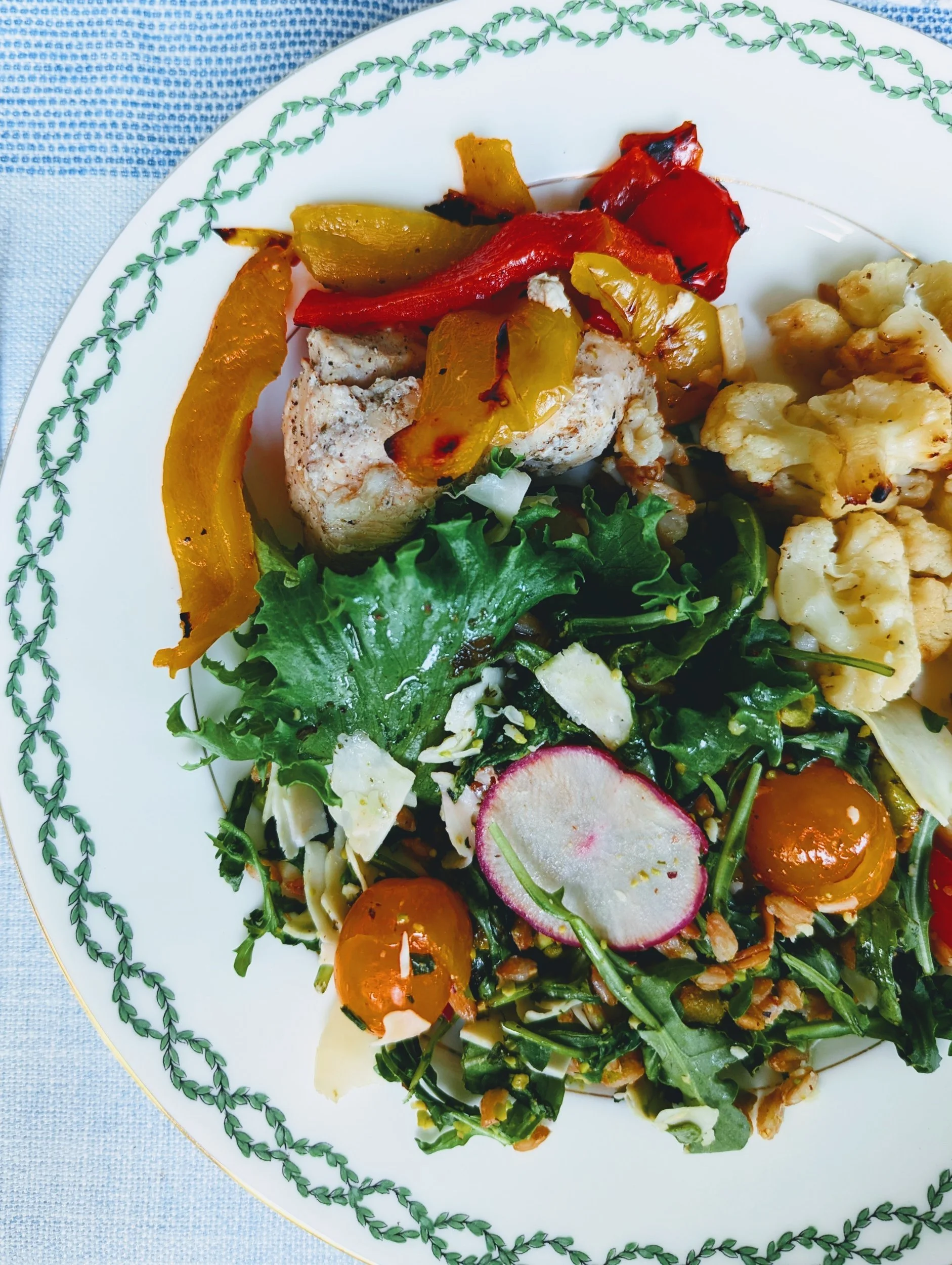 Dinner plate of roasted peppers, chicken, cauliflower and a salad of greens, radish and cherry tomatoes