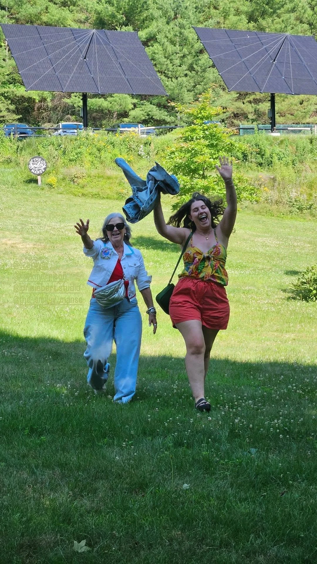 Two retreat artists running and cheering across the sunny lawn with solar panels in the background