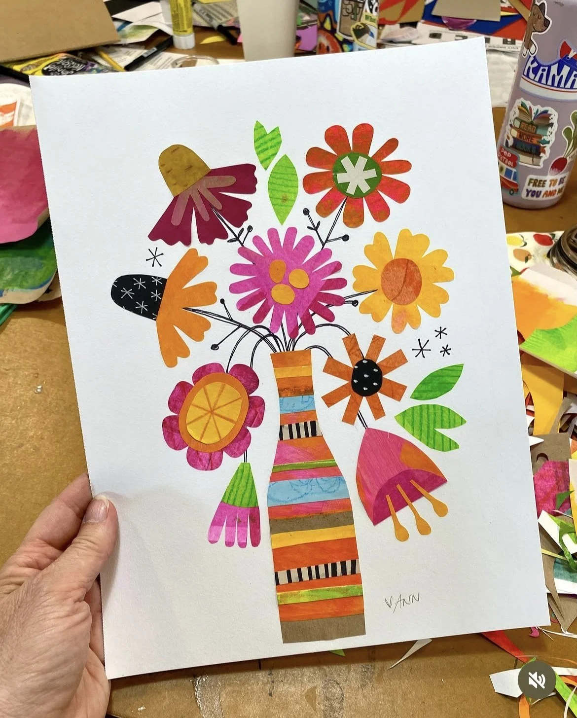 Hand-cut paper collage of a colorful flower bouquet in a striped vase, held up in the barn studio