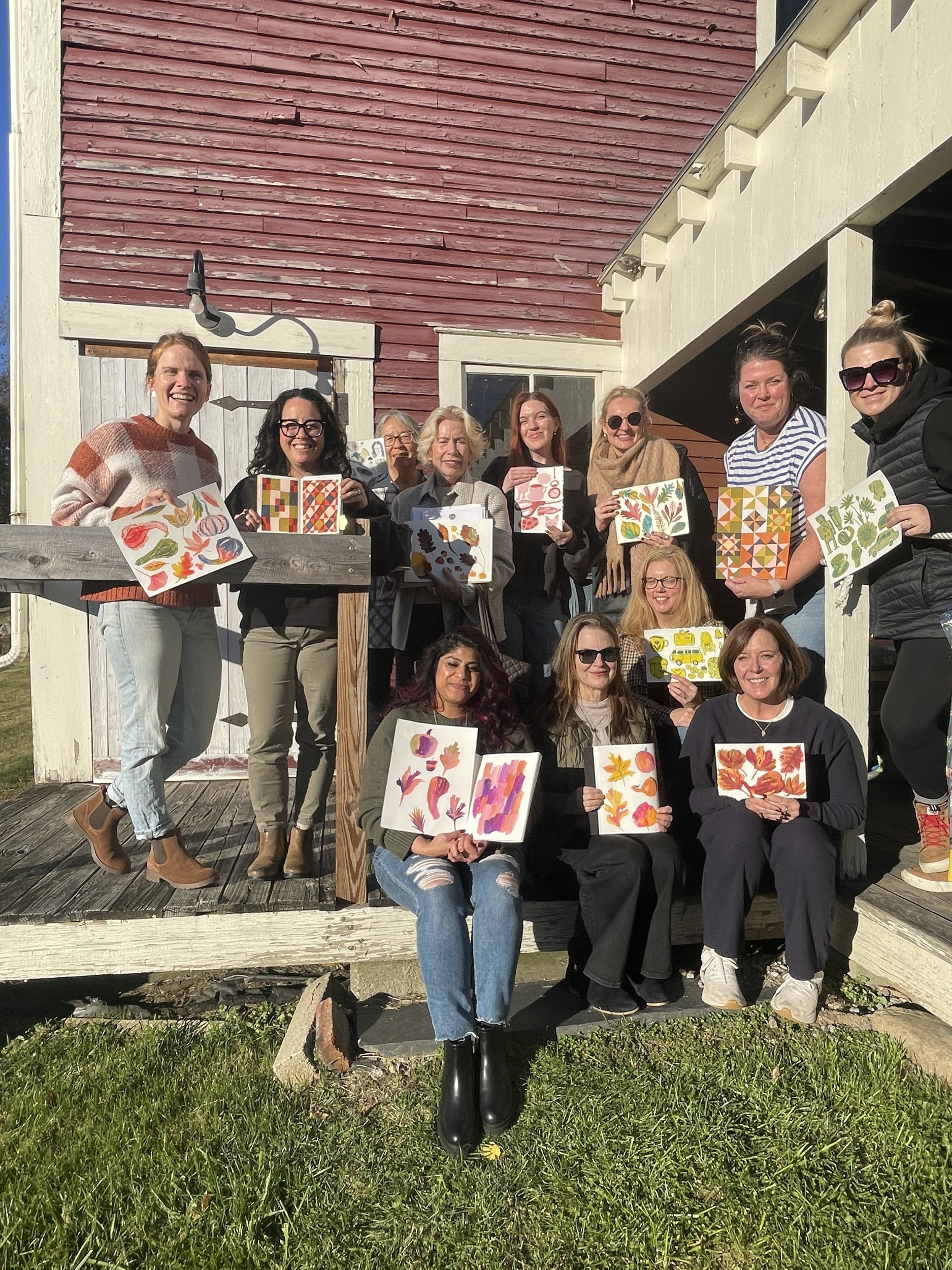 Group of retreat artists on the barn steps holding up their finished watercolor leaf paintings