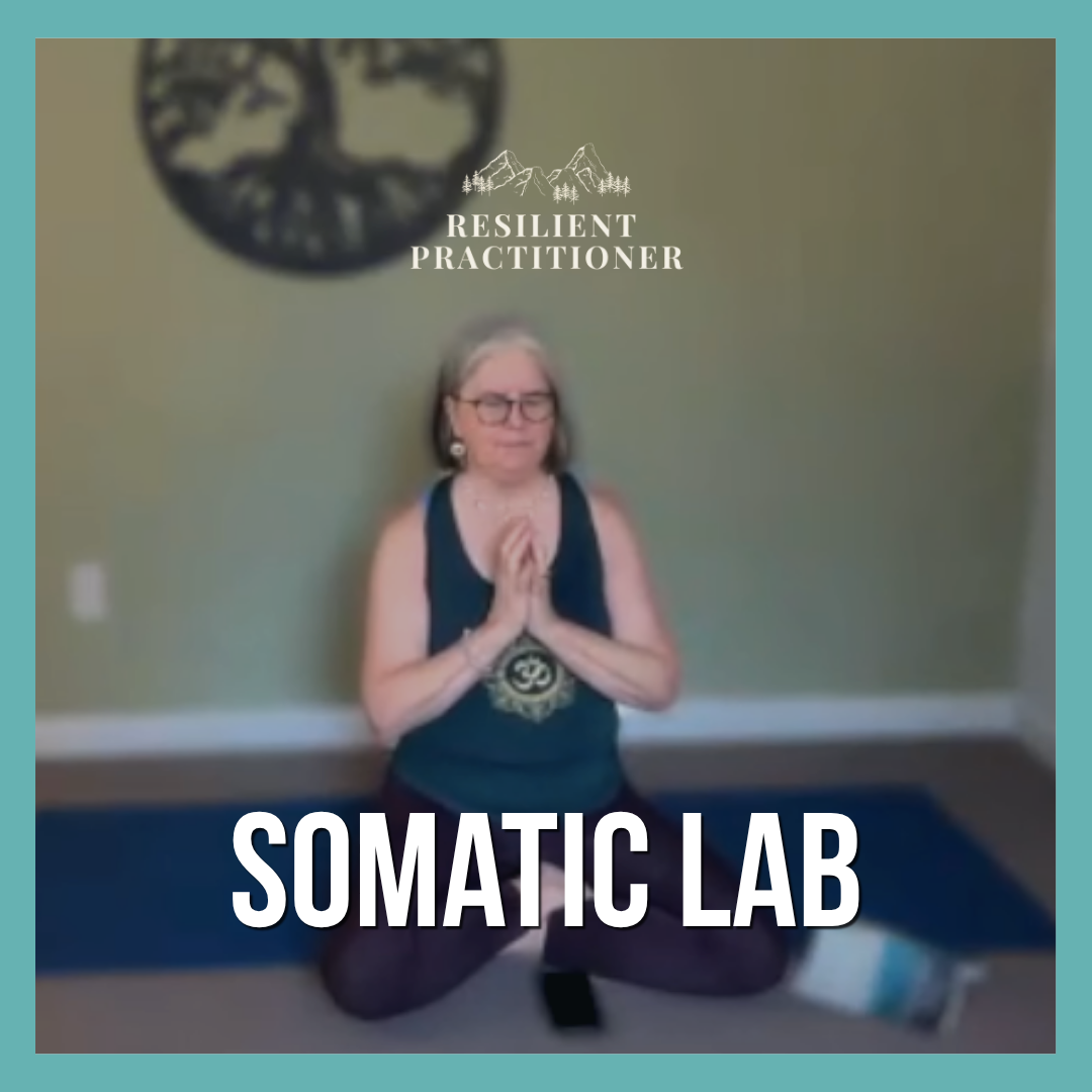 A woman practicing yoga or meditation in a room with a green wall, wearing glasses, a black tank top, and patterned leggings, sitting in a kneeling position with hands pressed together in prayer pose, with a circular wall decoration and a logo with mountains and trees behind her.