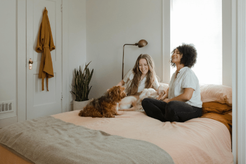 feeling let down by friends; two women sitting on bed laughing with a dog
