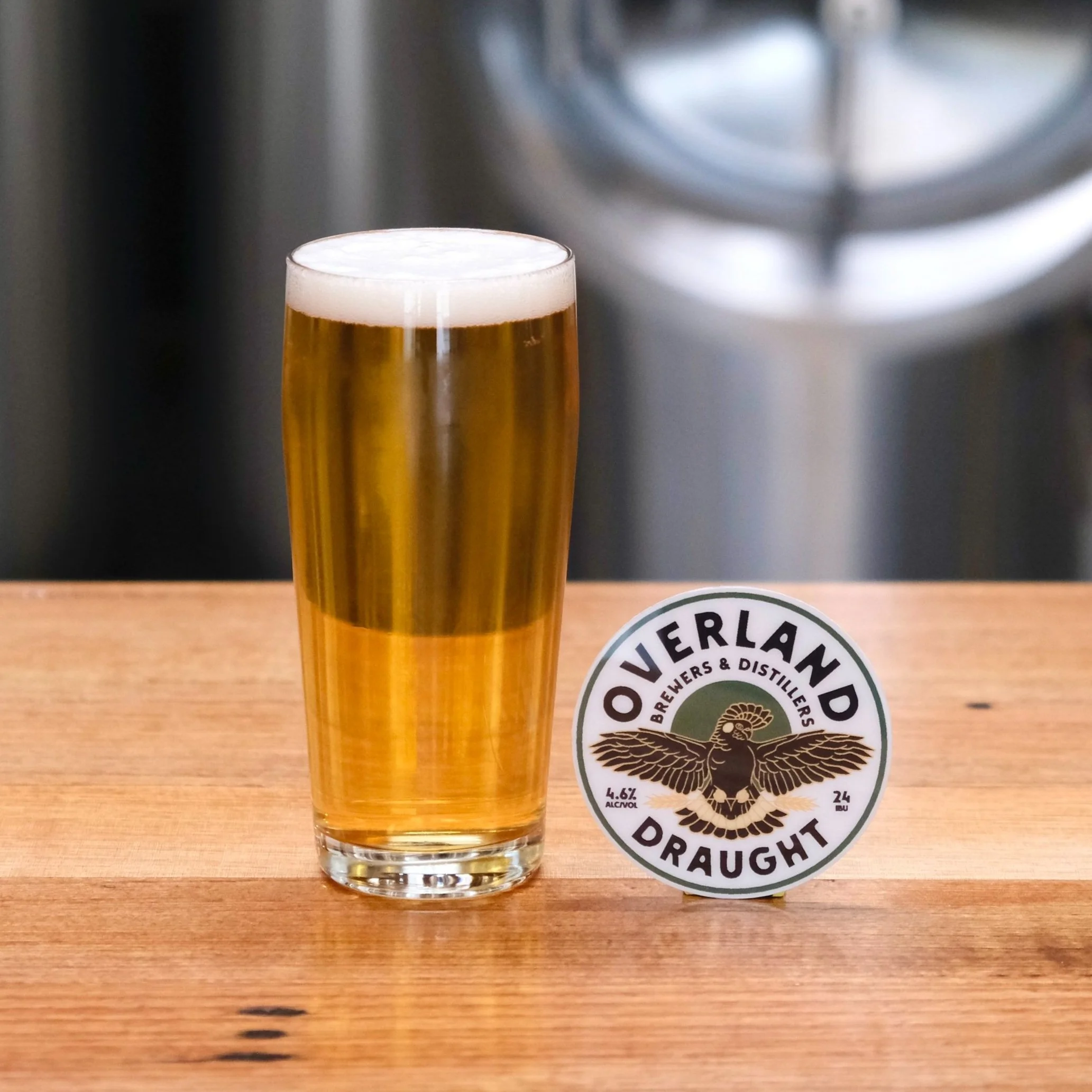 Pint of transparent gold beer and tap decal with black cockatoo logo