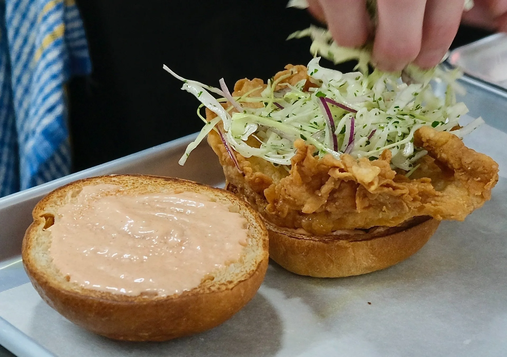 chef stacking fried chicken burger and cabbage slaw