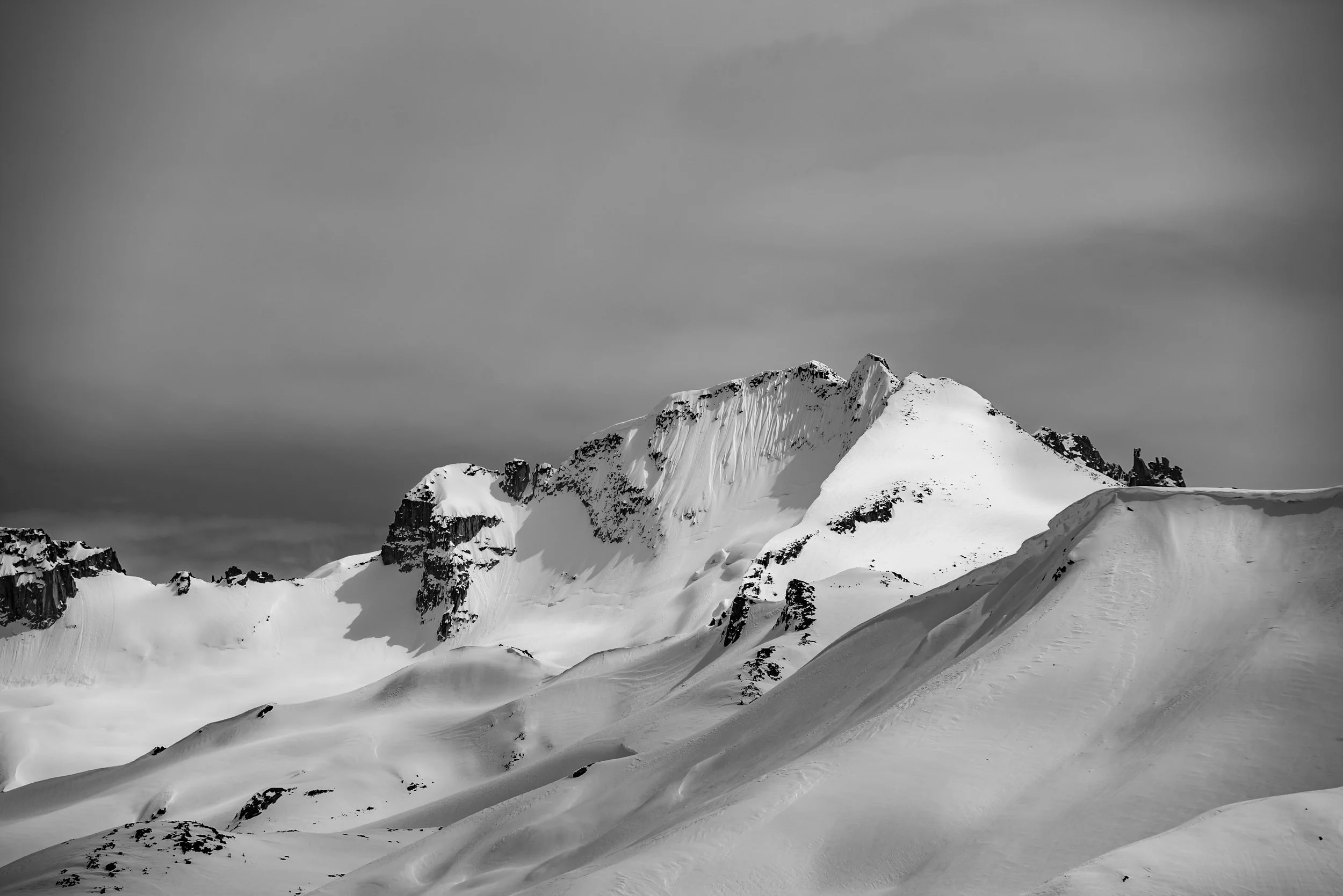 Snow-covered mountain range under a cloudy sky.