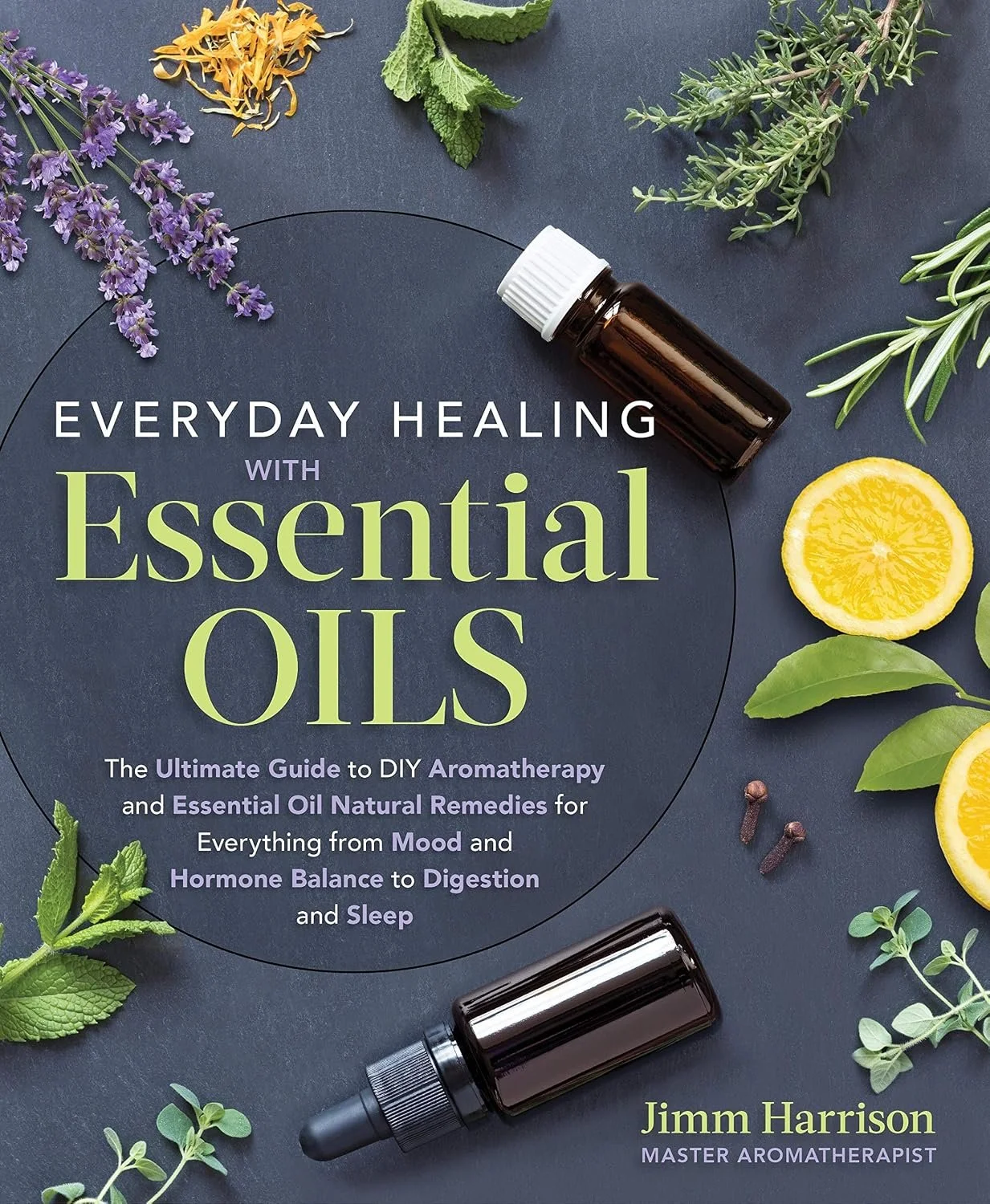 Book cover titled "Everyday Healing with Essential Oils" by Jimm Harrison, Master Aromatherapist, surrounded by fresh herbs, lemon slices, essential oil bottles, and dried flower petals on a dark background.
