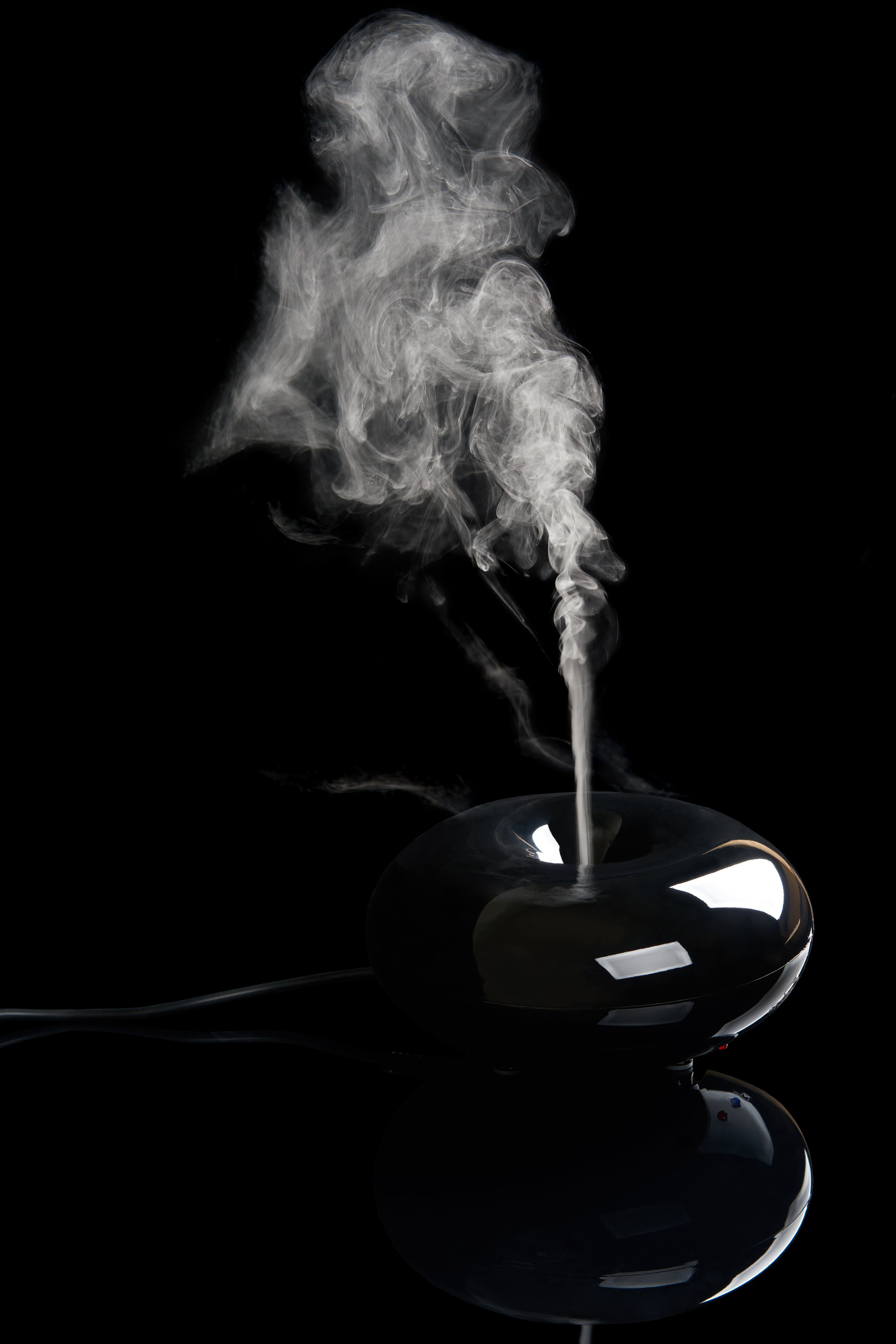 Smoke from Ultrasonic Aroma Diffuser and colorful light on black background.  Color Steam moving in dark. Real Artificial smoke in Colorful light on  black. Represent mood and tone feeling of Cyber punk