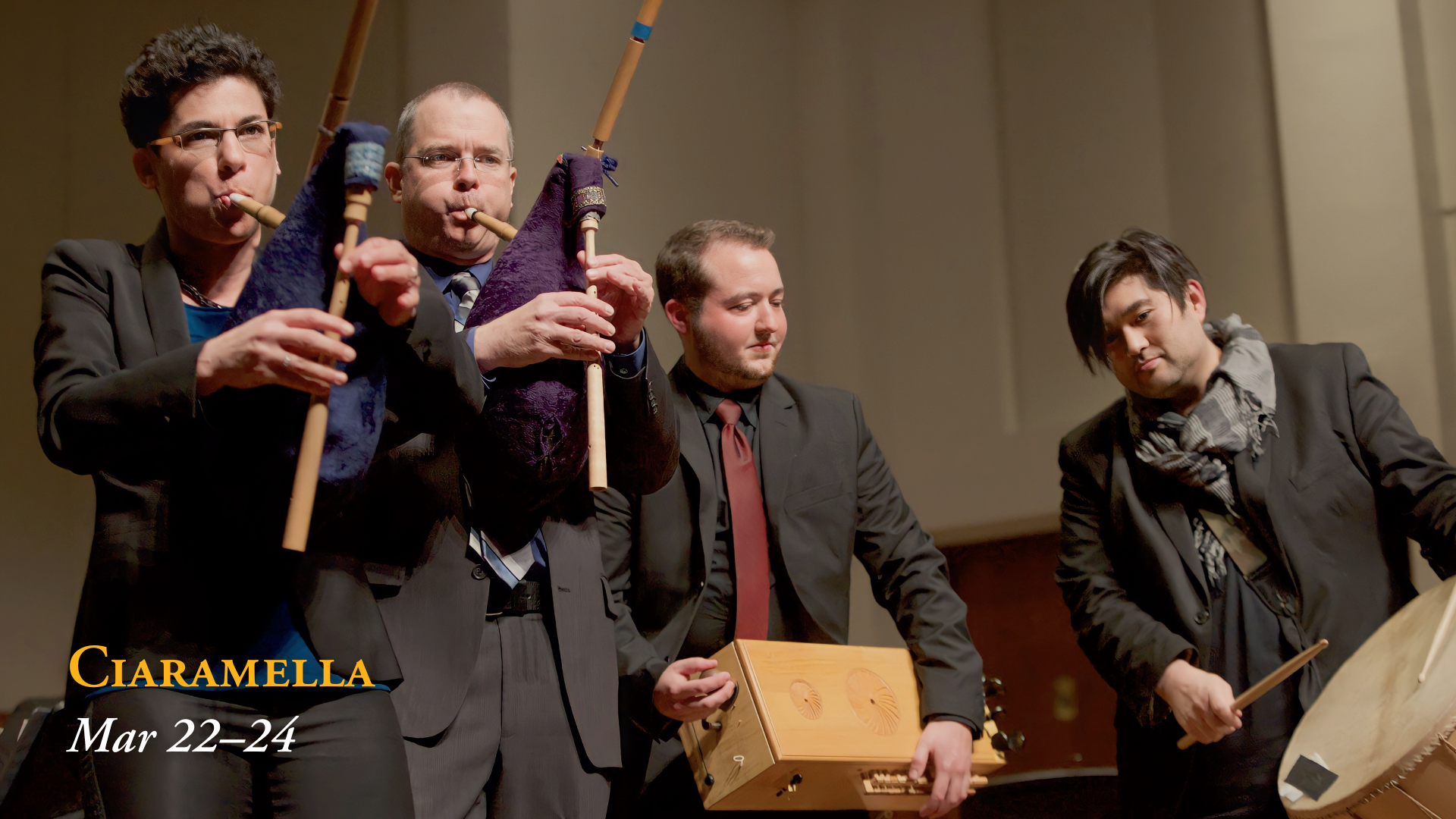 Four musicians performing on stage, playing a collection of traditional wind and percussion instruments.