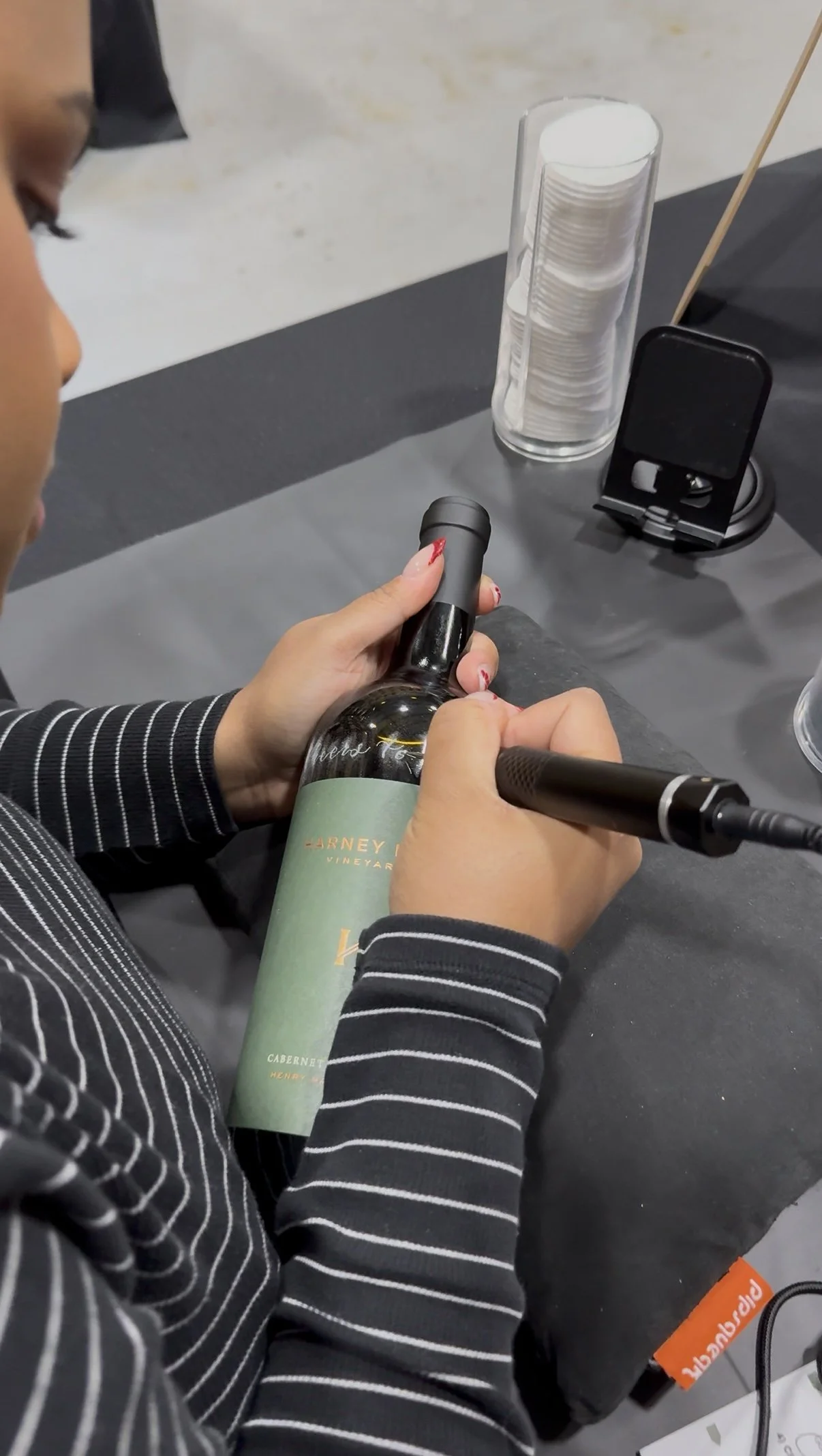 Person hand engraving a wine bottle at a tasting event.