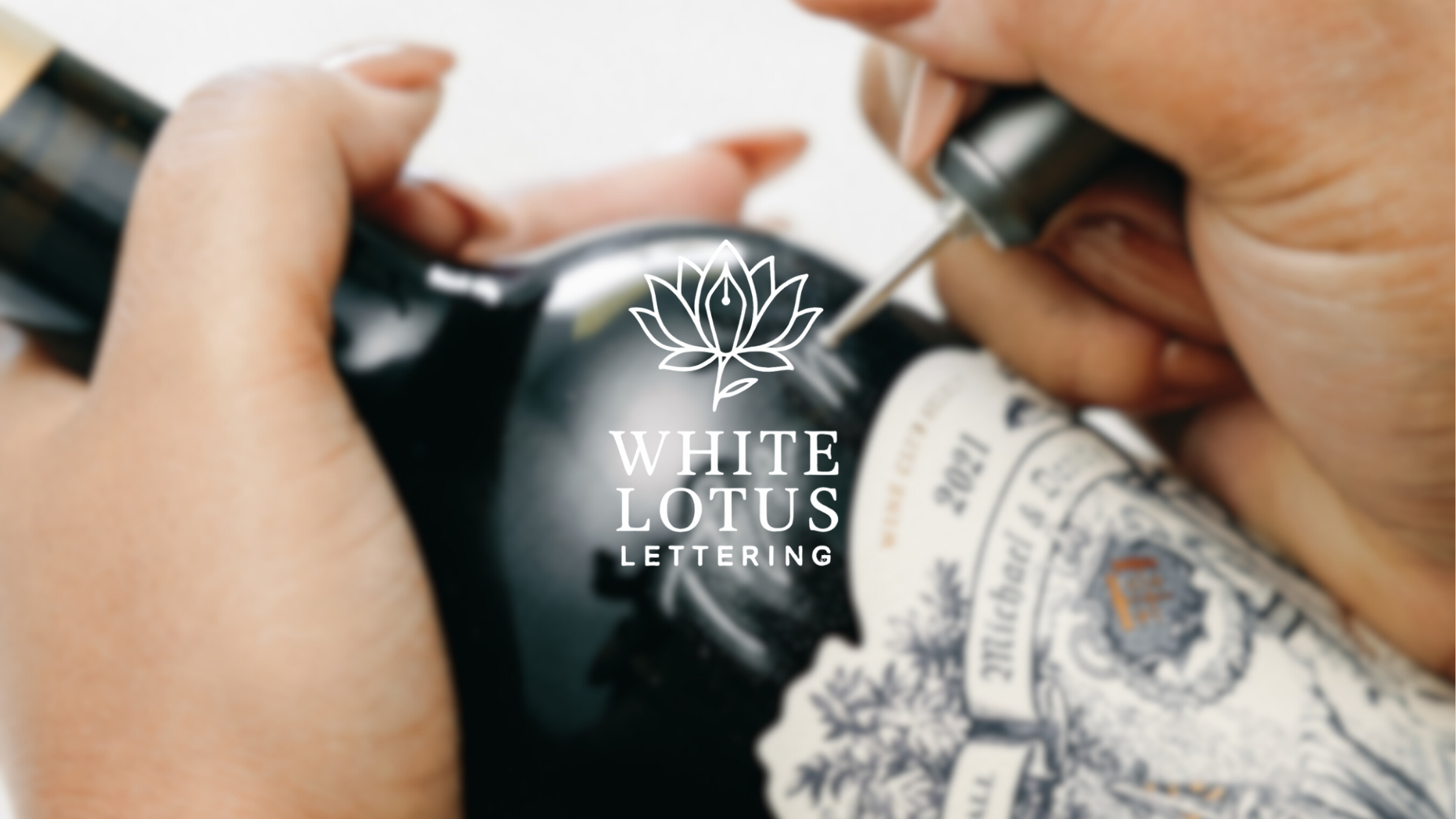 Close-up of someone hand engraving on a Michael David winebottle with a tool, with a logo for White Lotus Lettering center of the image.