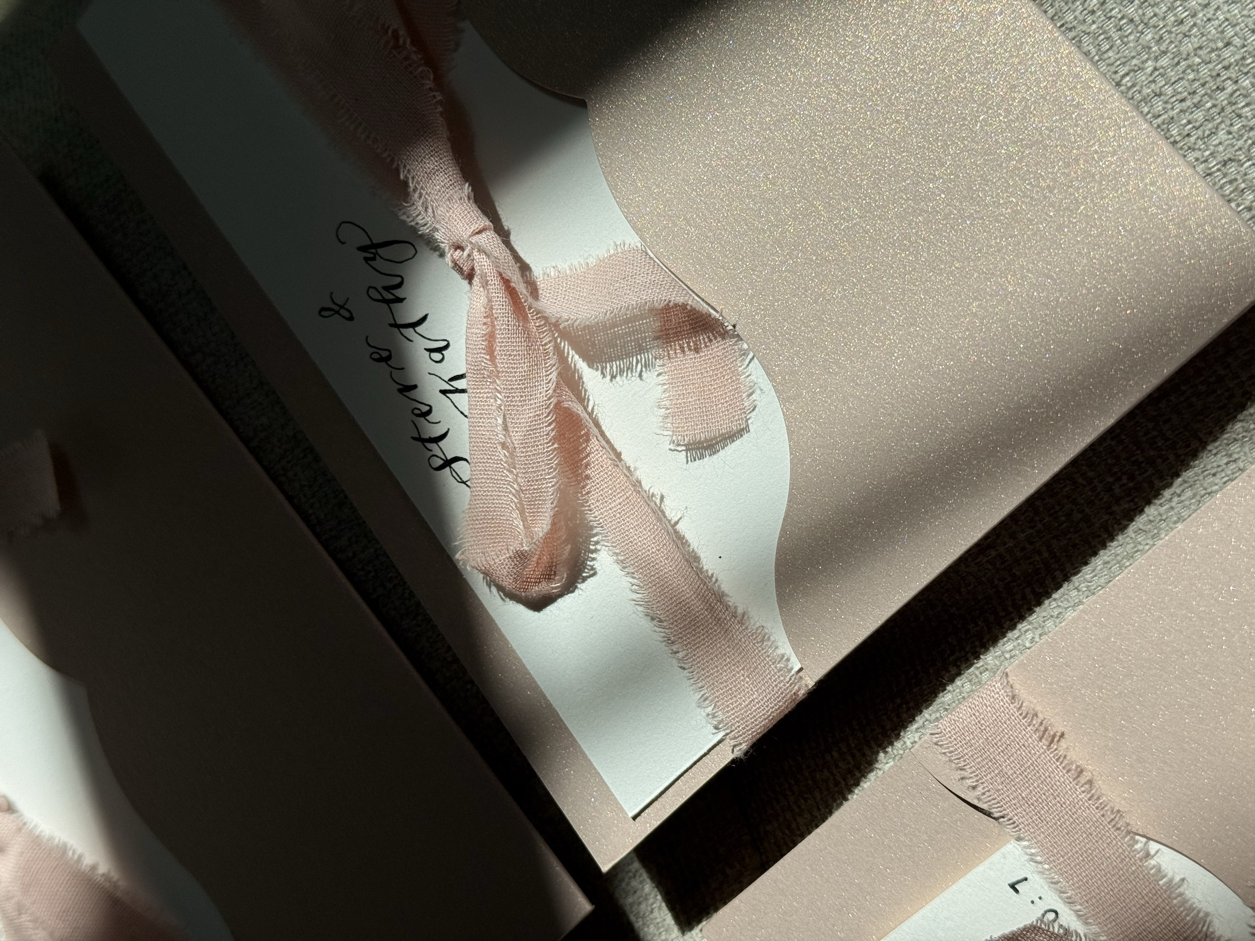 Close-up of a pink envelope with a textured surface, tied with a pink ribbon and a handwritten thank you card.