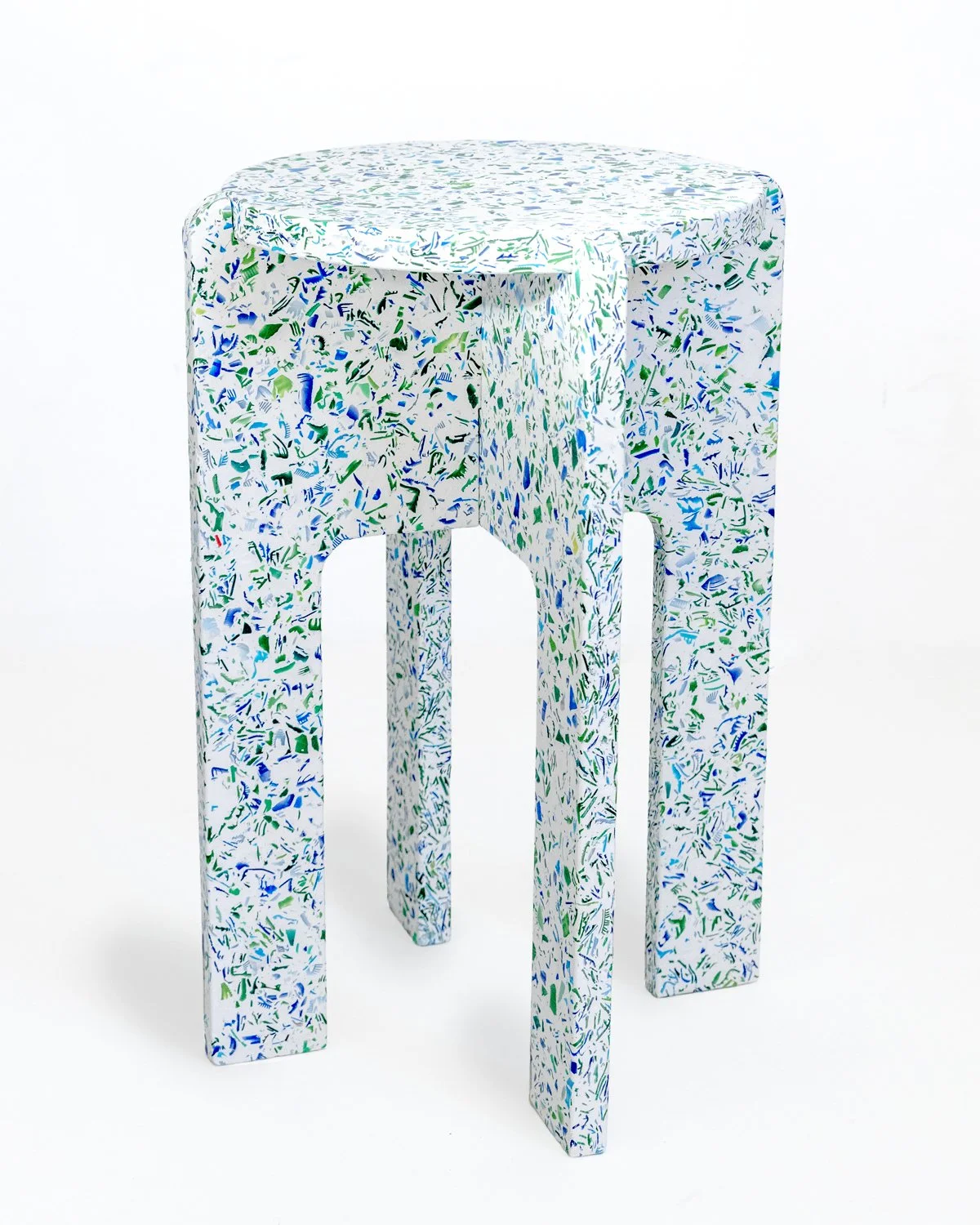 Un tabouret, dans le tons froids, conçu à partir de gypse, dans un rendu terrazzo en bouchons de bouteilles en plastique.