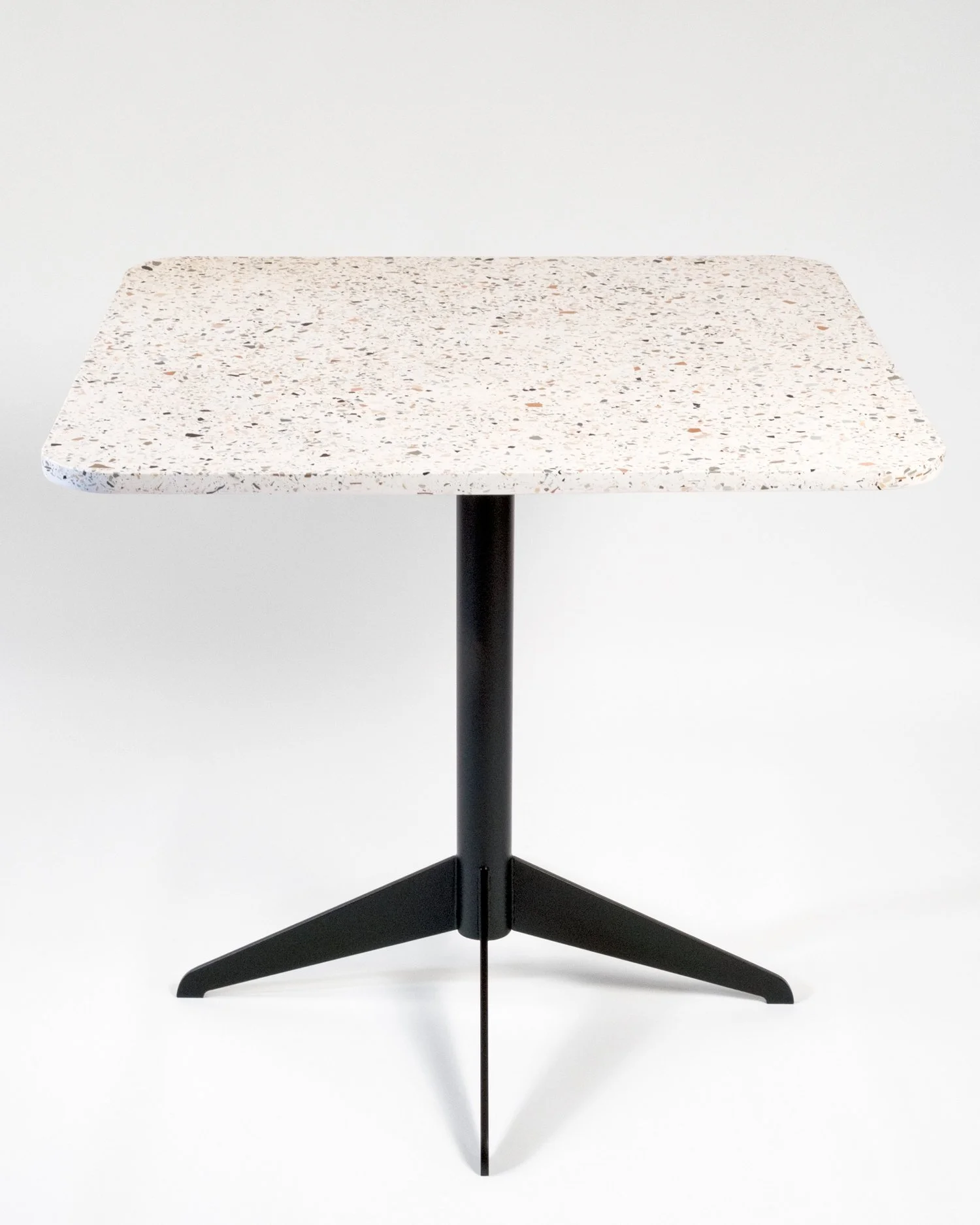 Table avec un plateau en composite terrazzo et un piètement en métal noir.