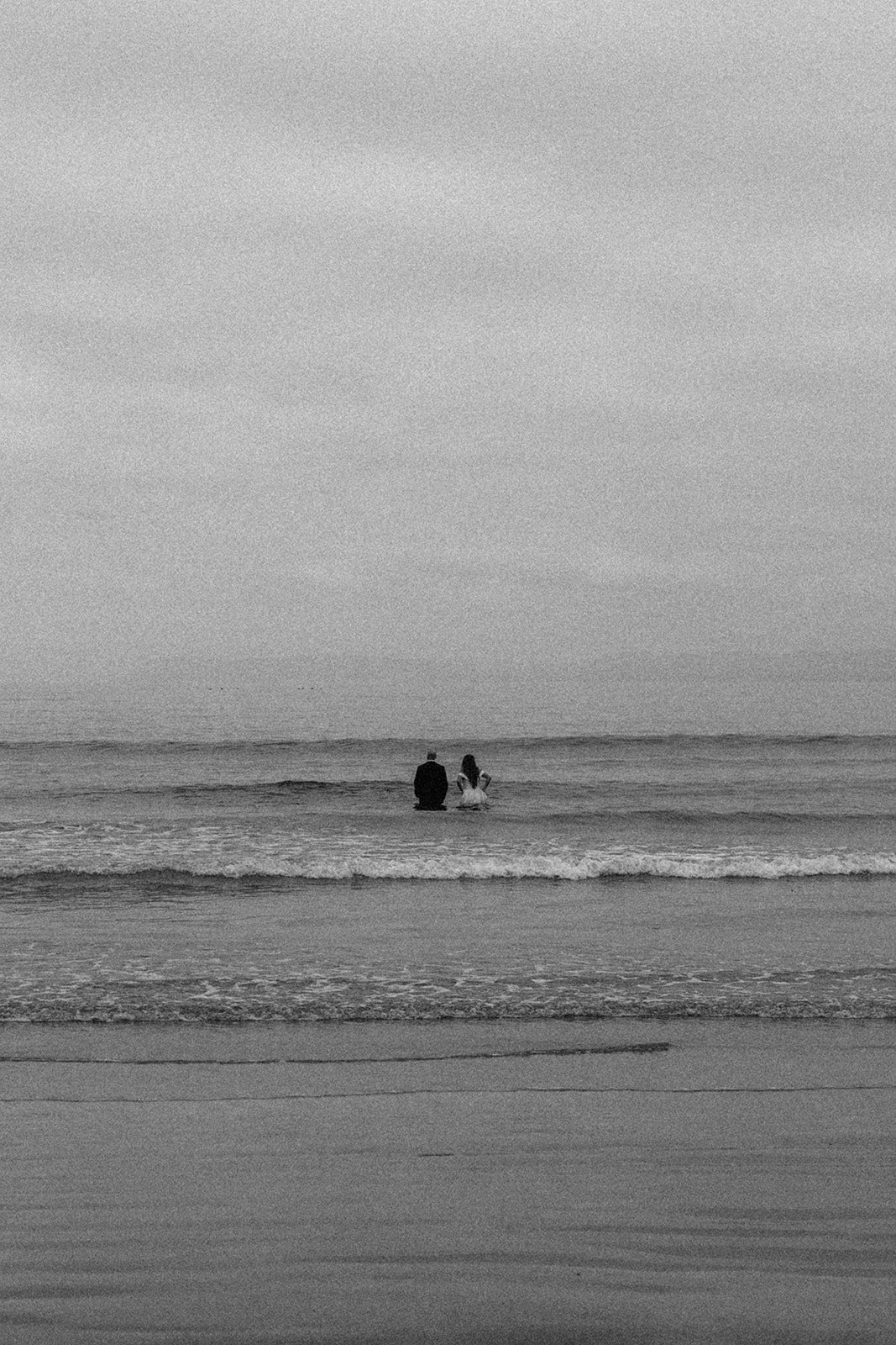 Black and white film photo of couple in the ocean