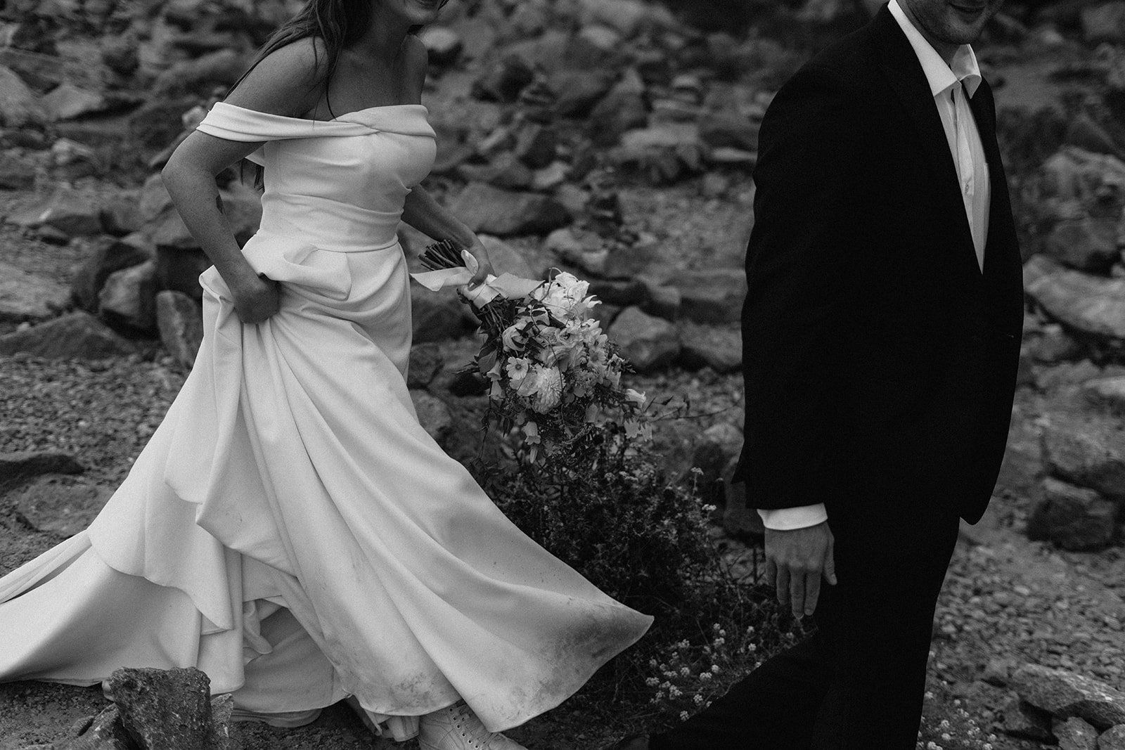 Black and white film photo of couple walking through rocks