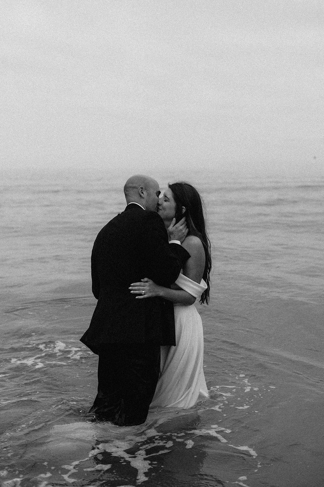 Couple kiss in the ocean while they elope