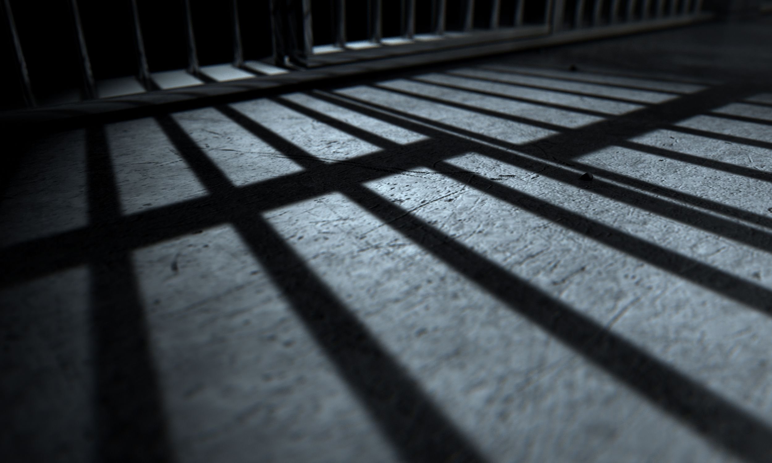 Shadows of jail bars cast across a concrete floor, representing arrest and the seriousness of Illinois drug charges.