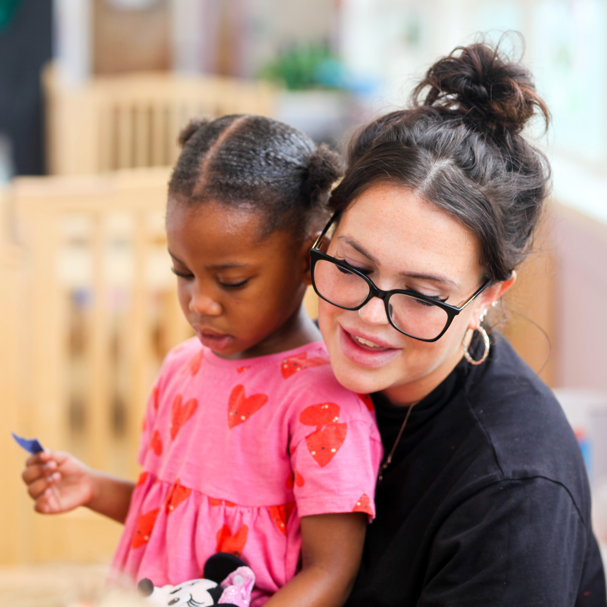 A young girl sat with a young woman playing