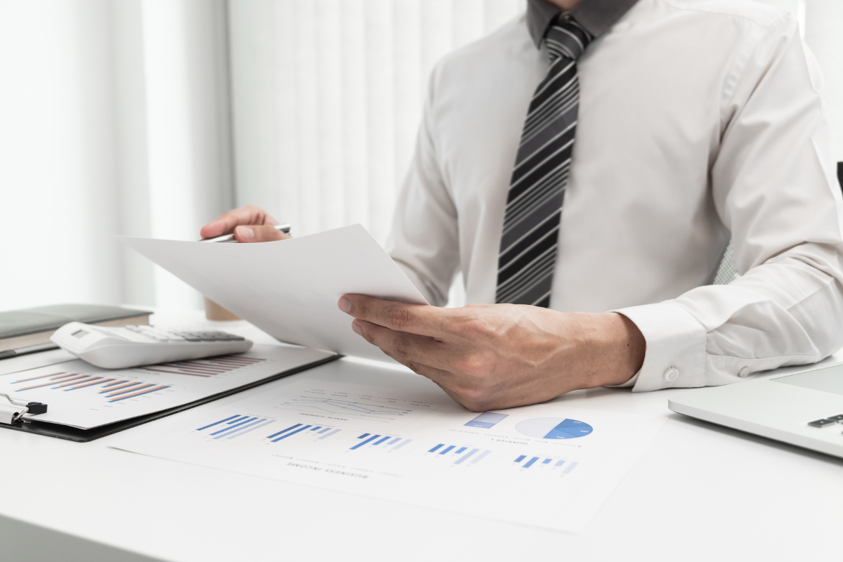 Man at a desk with papers and graphs and a calculator