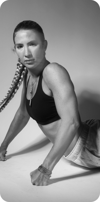 Sydney with braided hair doing a workout on the floor, wearing a sports bra and sweatpants, in black and white.