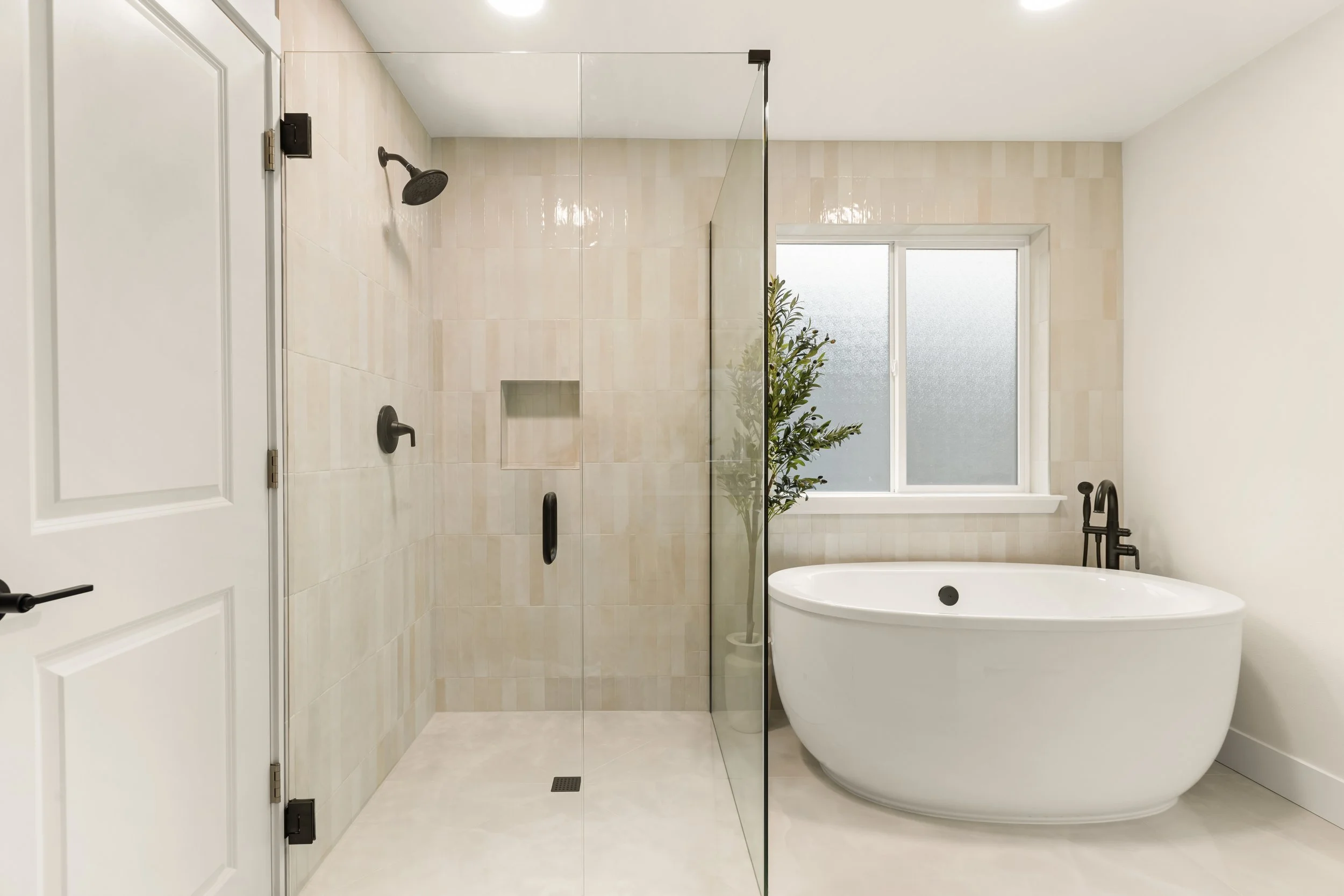 Modern bathroom with a walk-in shower and a freestanding bathtub, a potted plant, and a window with frosted glass.