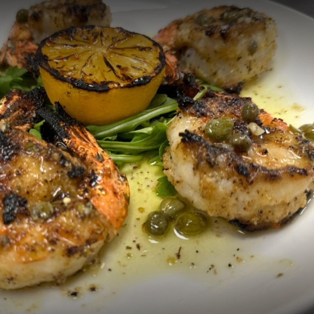 Grilled chicken with lemon, capers, and herbs, served with roasted potatoes and greens.