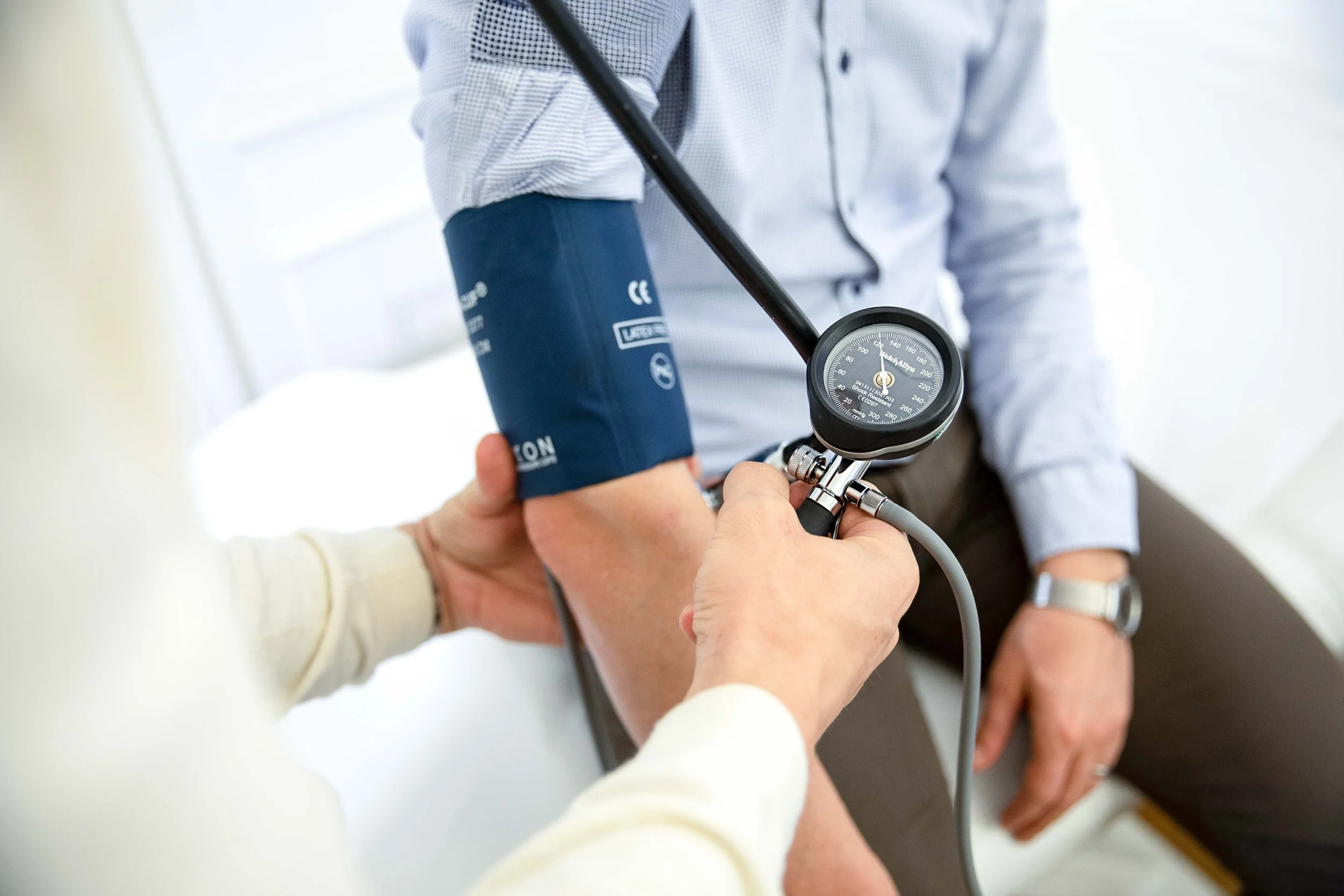 Doctor measuring a patient’s blood pressure with a sphygmomanometer during a health check-up, emphasizing preventive care and medical assessment.