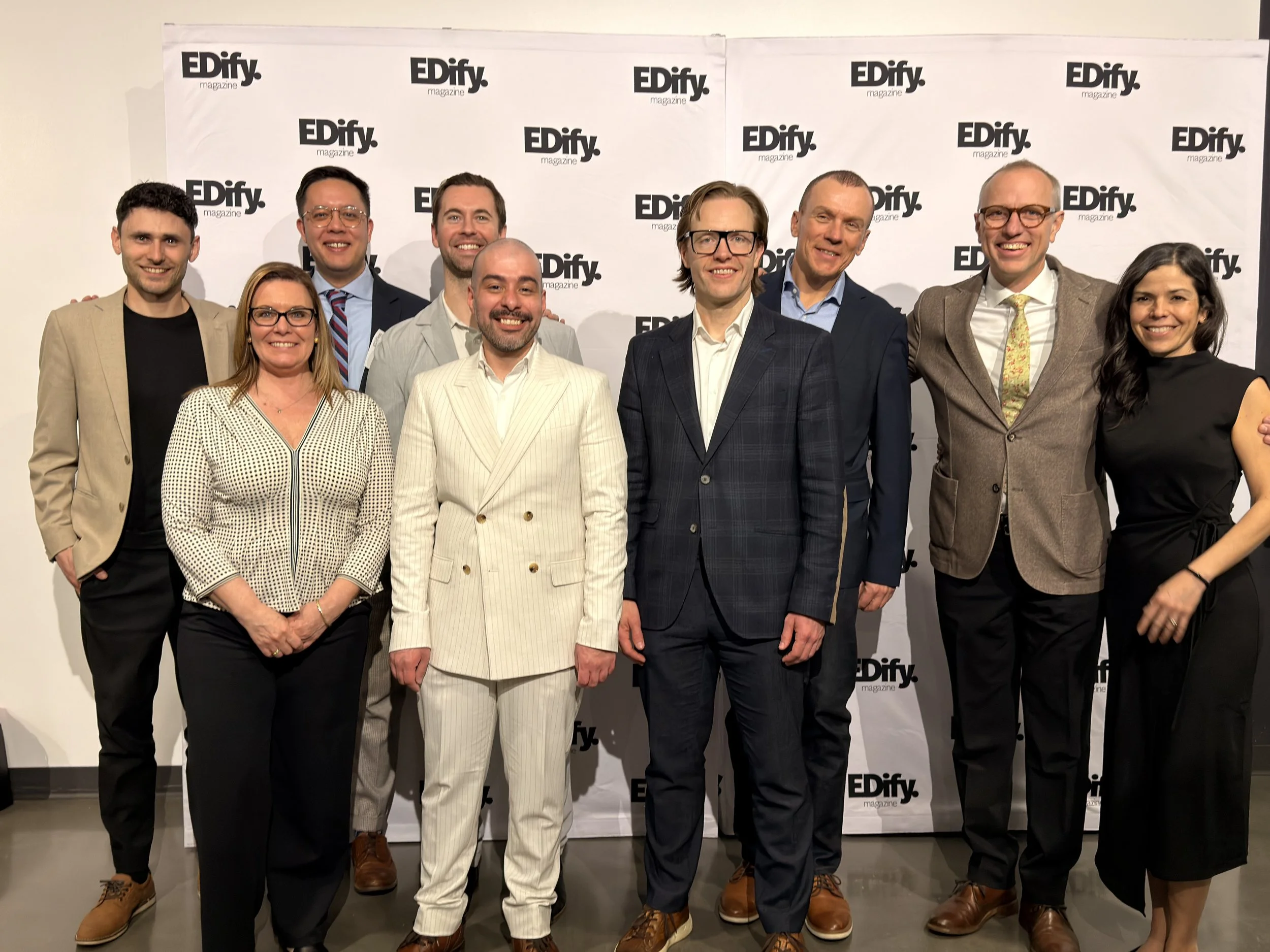 Group of nine people standing in front of a white backdrop with black logo text that reads 'EDify magazine'.