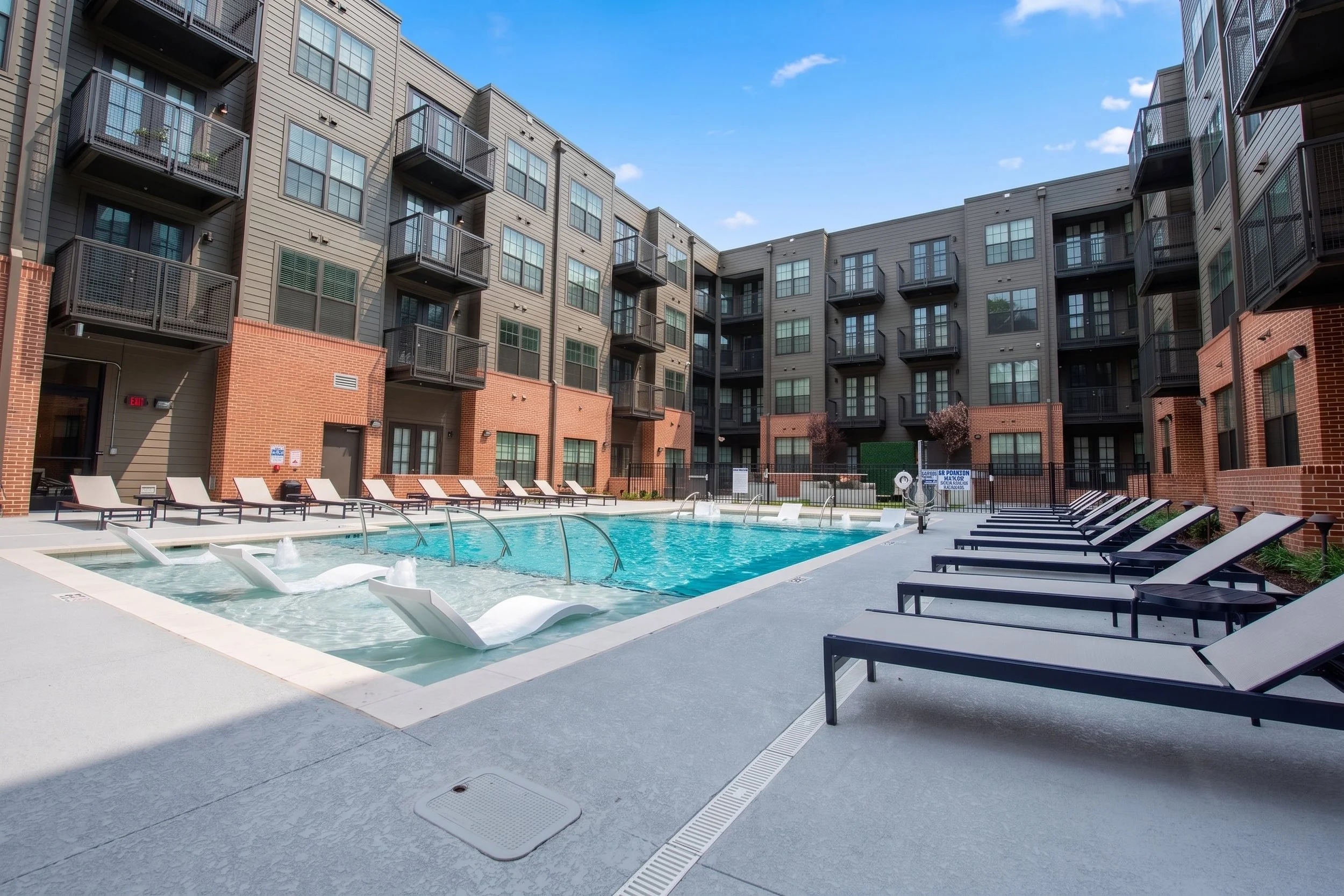 A large outdoor swimming pool area with lounge chairs, surrounded by the Easley apartments, a modern multi-story apartment building with balconies. 