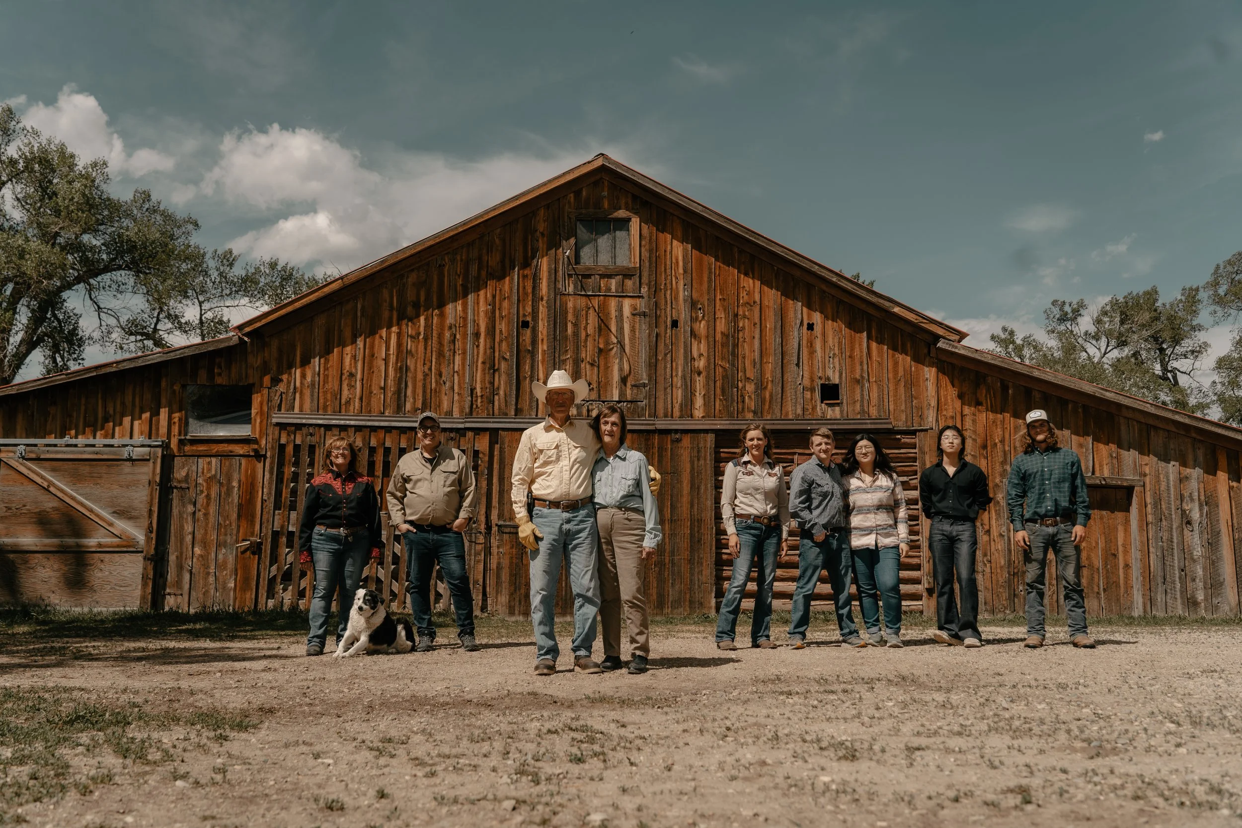 The TA Ranch family standing in front of the historic 1800s wooden barn on a farm. TA Ranch, guest ranch, dude ranch, working cattle ranch, horse ranch, horseback riding, Buffalo Wyoming North-eastern Wyoming, homestead, agriculture