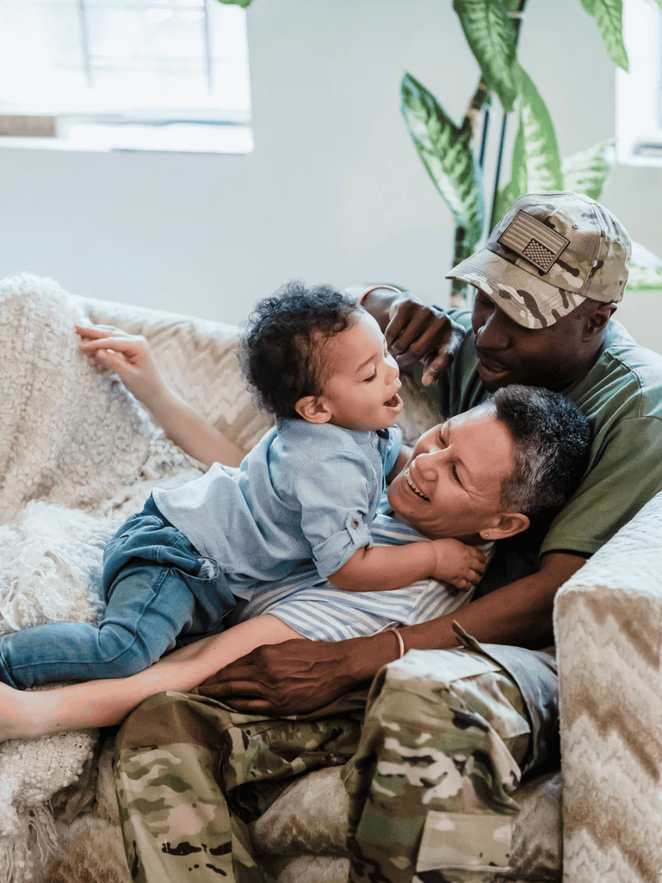 Veteran father in uniform laughing with his children on the couch