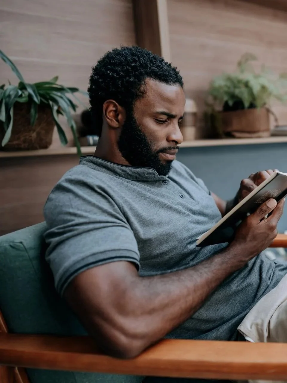 Man relaxing in a chair, reading on a tablet