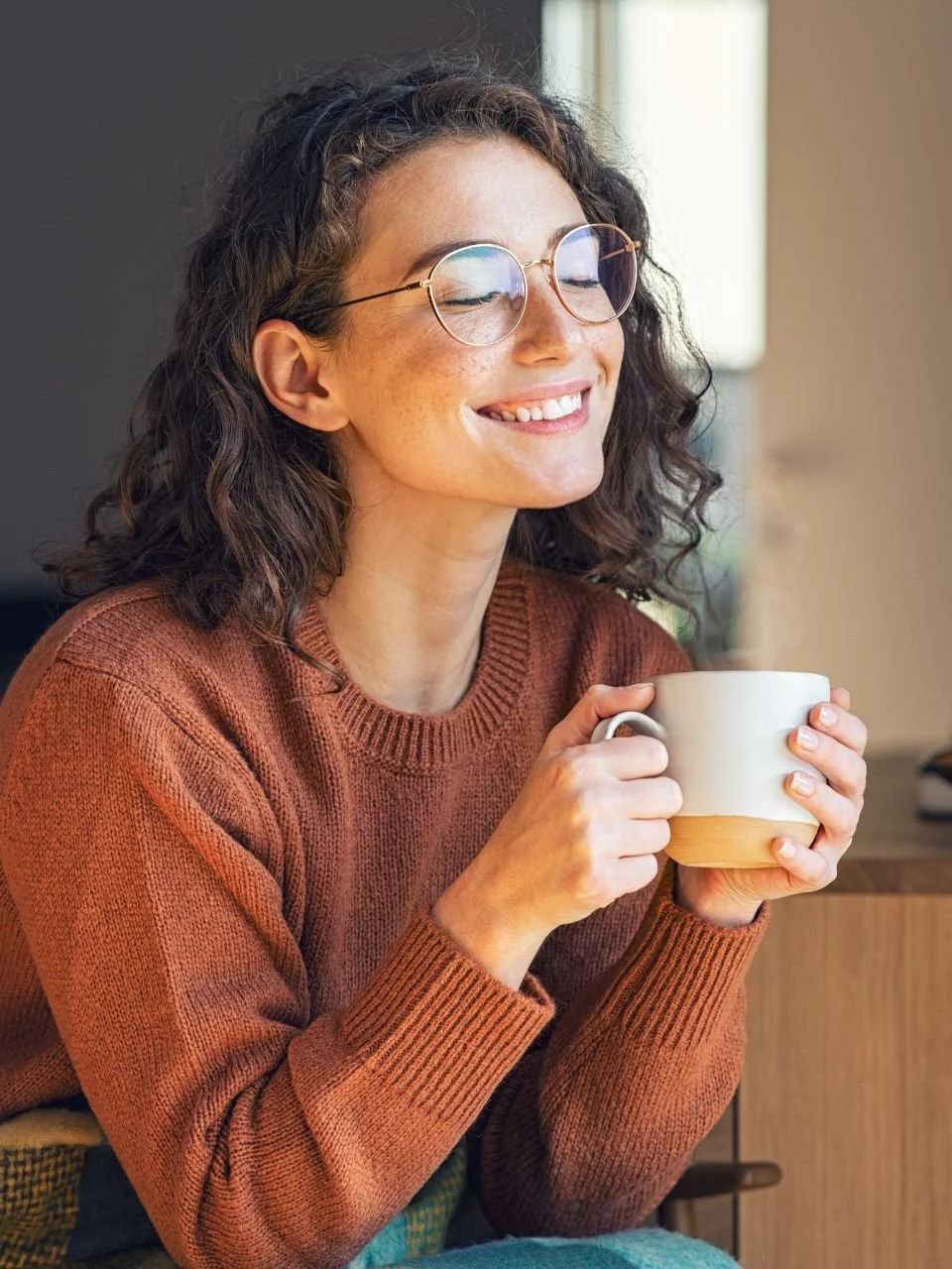 Woman smiling with eyes closed, holding a warm mug