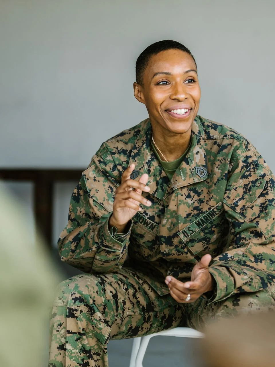 Service member in camouflage smiling during a conversation