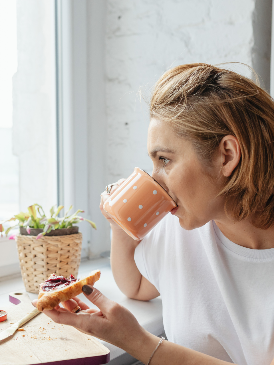 Woman taking a quiet moment with coffee by a sunny window