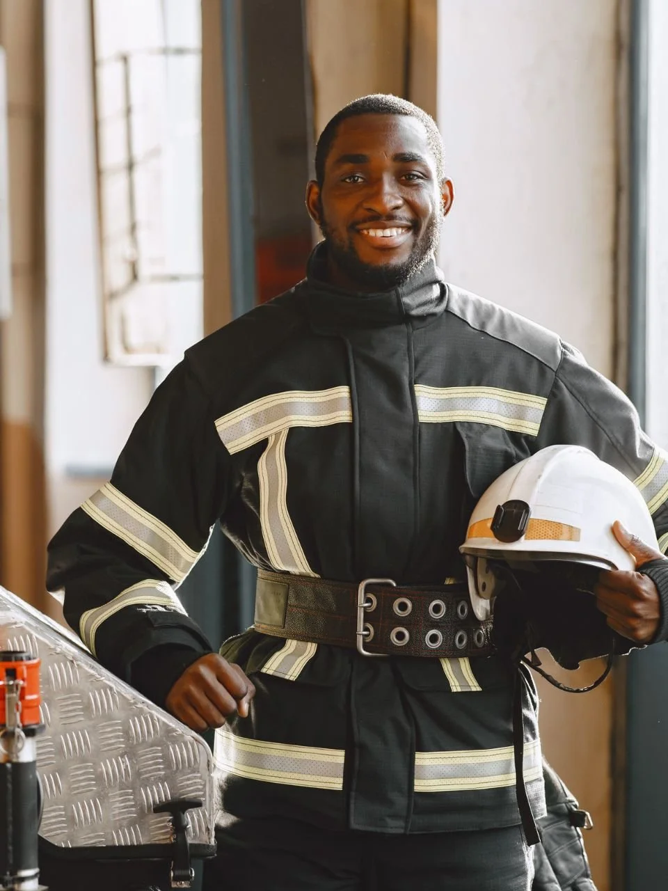 Smiling firefighter in turnout gear holding his helmet